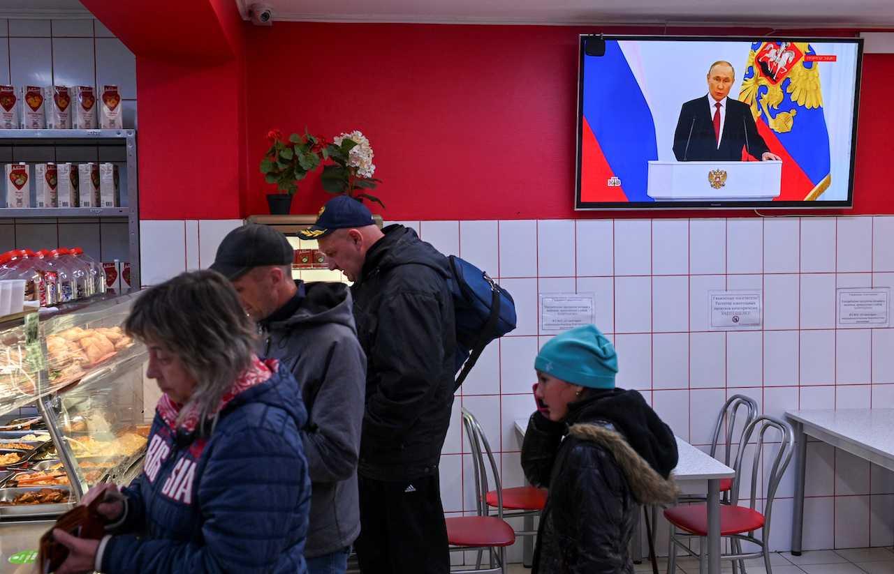 Russian President Vladimir Putin is seen during the broadcast of a ceremony to declare the annexation of the Russian-controlled territories of four Ukraine's Donetsk, Luhansk, Kherson and Zaporizhzhia regions, at a cafe in Omsk, Russia, Sept 30. Photo: Reuters