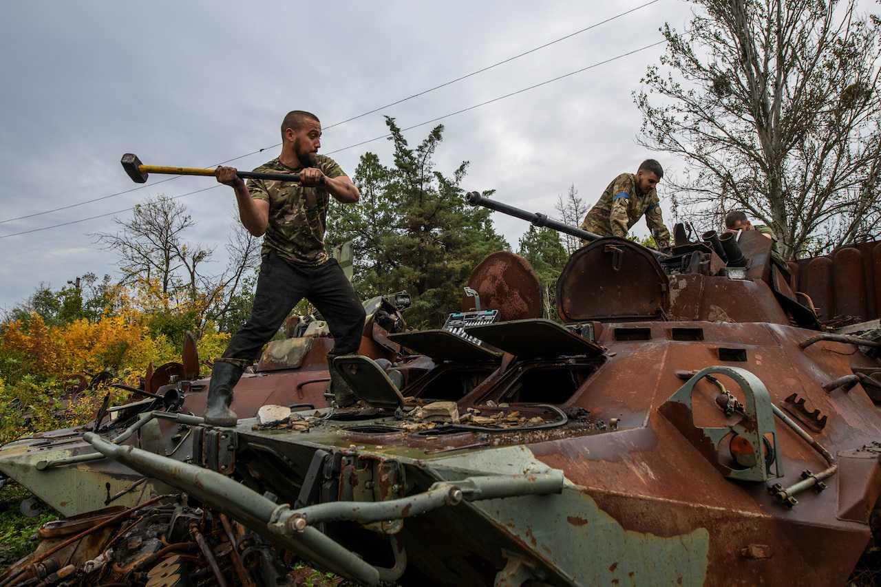 A Ukrainian service member dismounts a cannon from a captured Russian armoured personnel carrier, amid Russia's attack on Ukraine, near the town of Izyum in Kharkiv region, Ukraine, Oct 2. Photo: Reuters