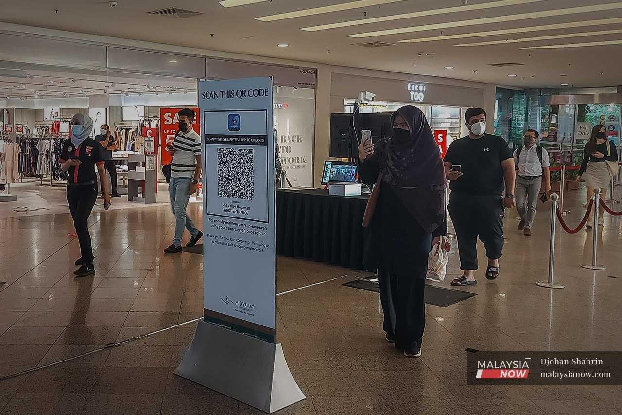 People use the MySejahtera application to scan the QR code for entry to a shopping mall in Kuala Lumpur. 
