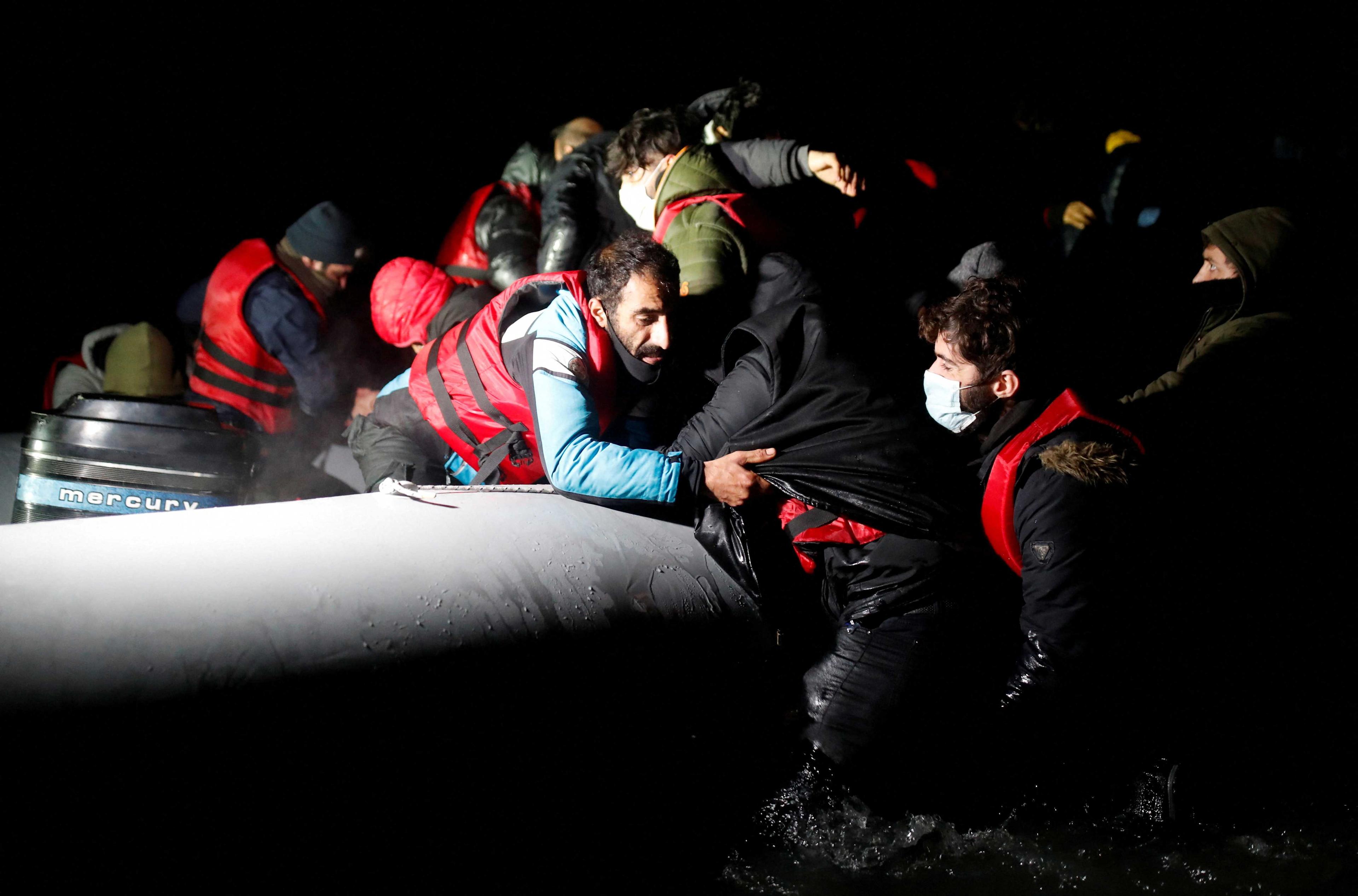 Migrants get on an inflatable dinghy as they leave to cross the English Channel, in Wimereux near Calais, France, Dec 16, 2021. Photo: Reuters