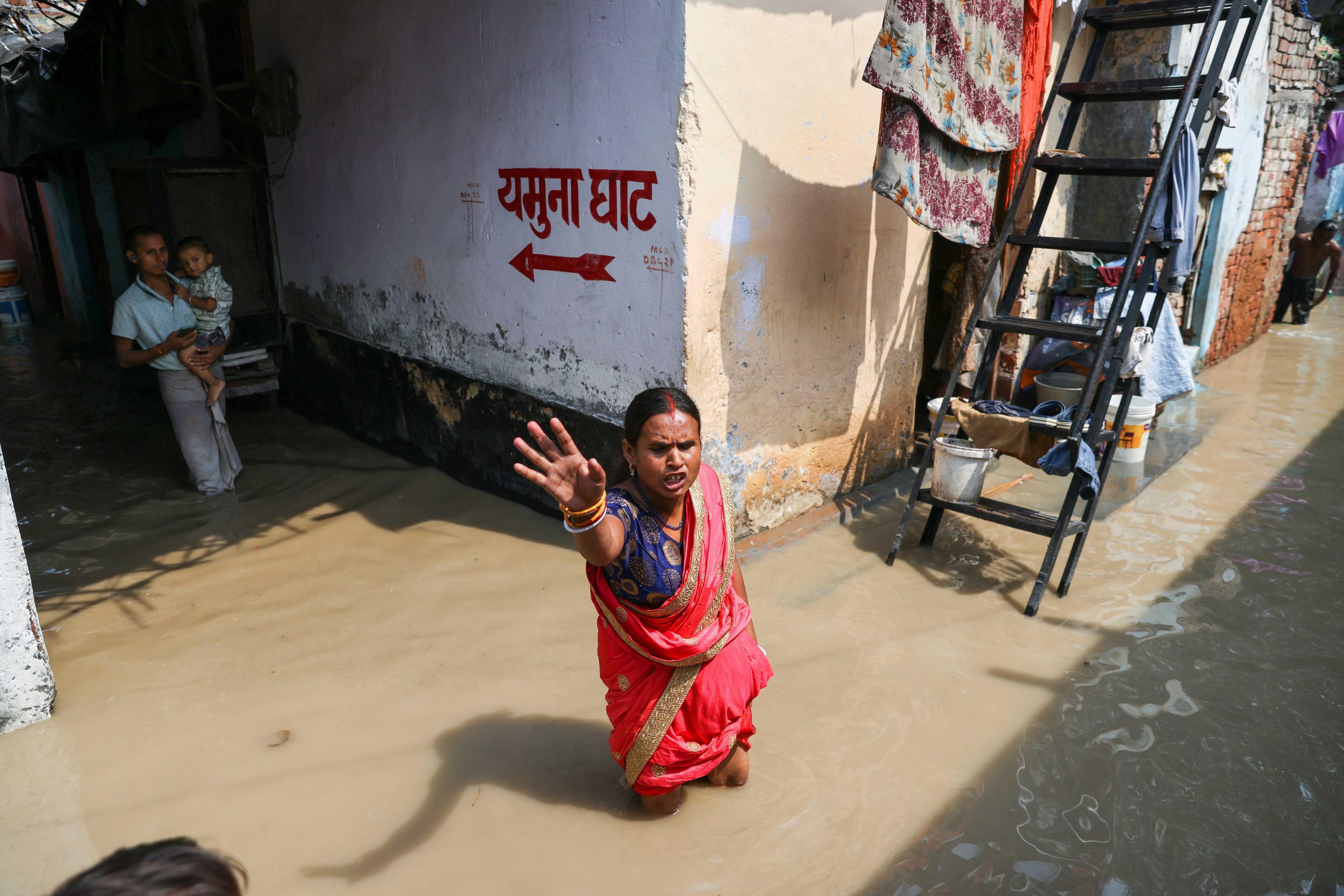 A woman reacts as she walks through a flooded lane on the banks of Yamuna River in Delhi, India, Sept 28. Photo: Reuters
