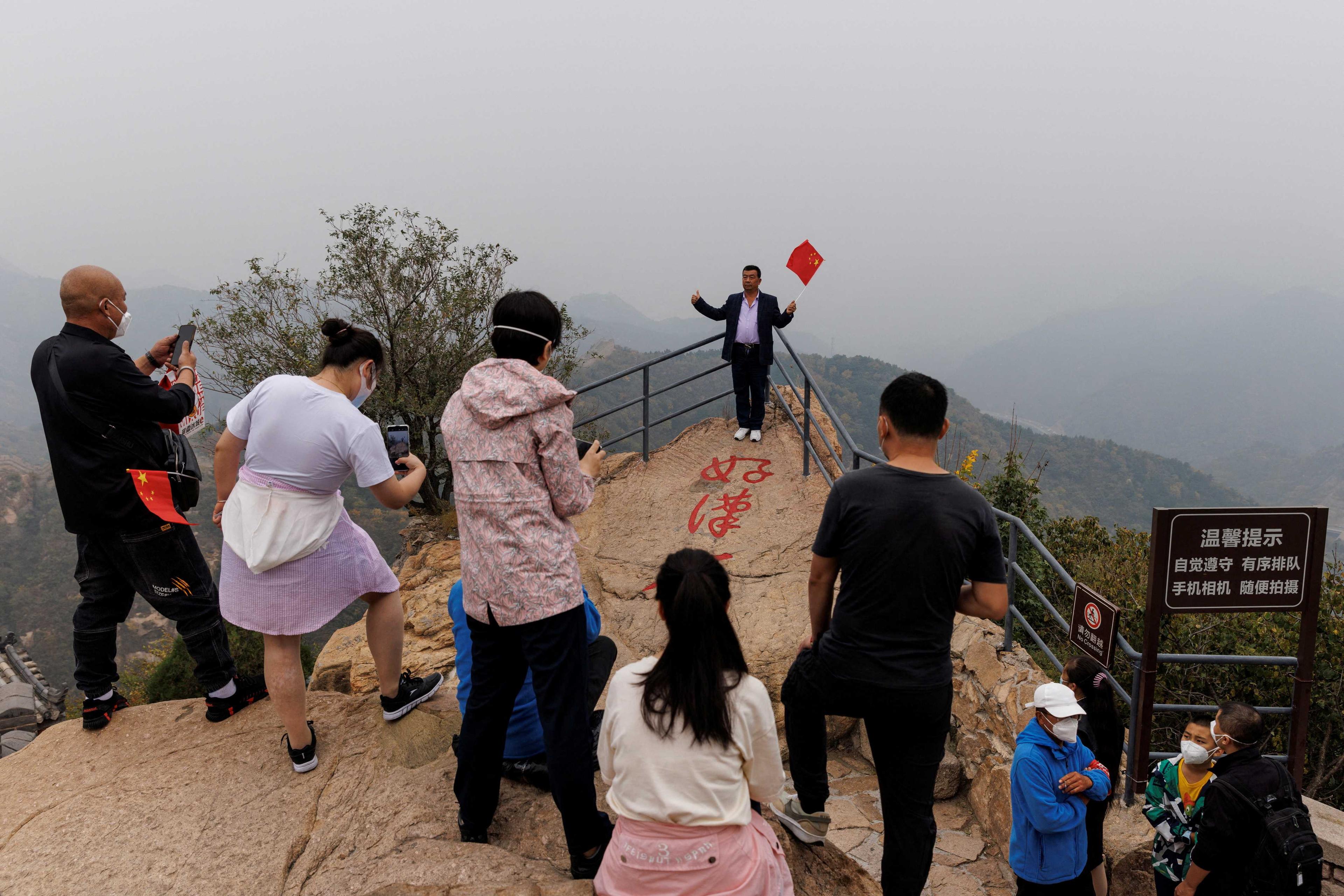 A man holds a Chinese flag as he poses for pictures on the Great Wall on National Day holiday following an outbreak of Covid-19 in Beijing, China, Oct 1. Photo: Reuters