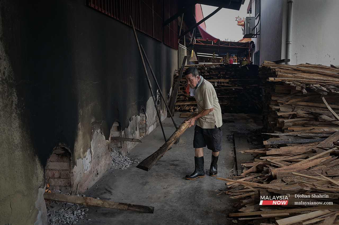 Seorang pekerja membawa masuk sebatang kayu bakar untuk kegunaan dapur.