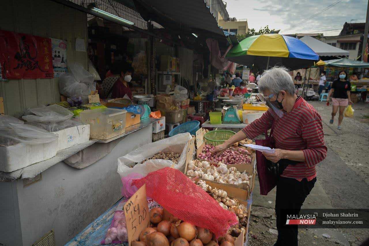 A woman stops to buy garlic at a sundry shop in the Ampang market in Selangor.