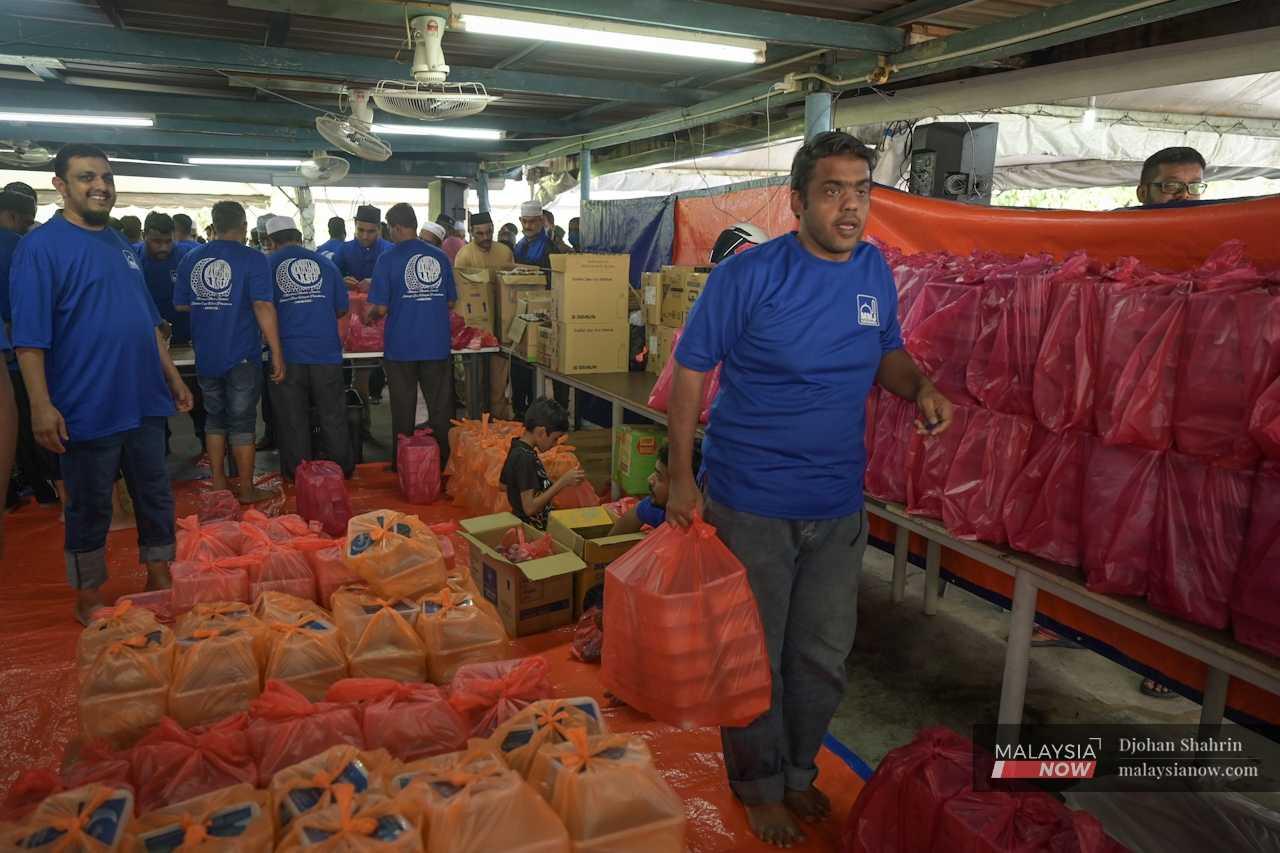 A secretariat member oversees the distribution of the thousands of containers of food.