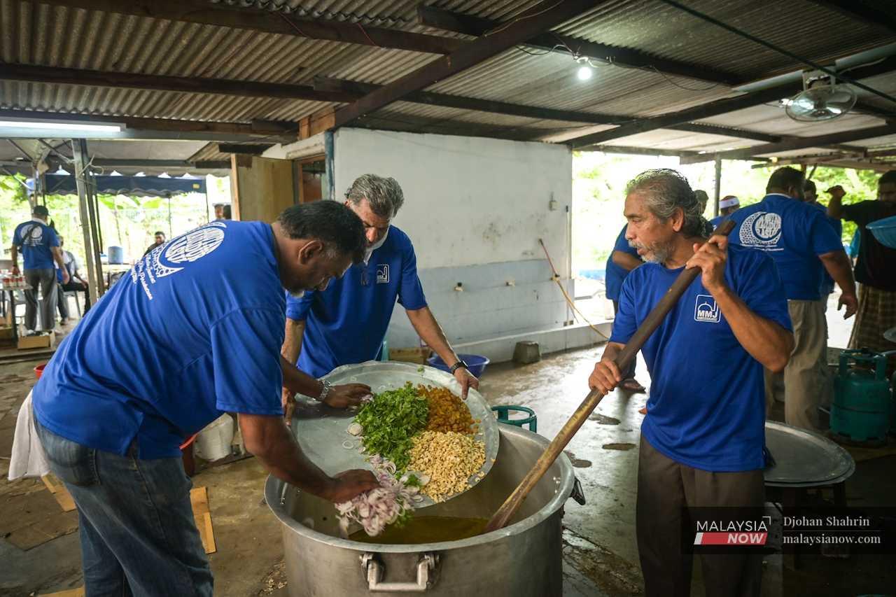 Sukarelawan memasukkan bahan masakan nasi maulud ke dalam periuk dengan berhati-hati.