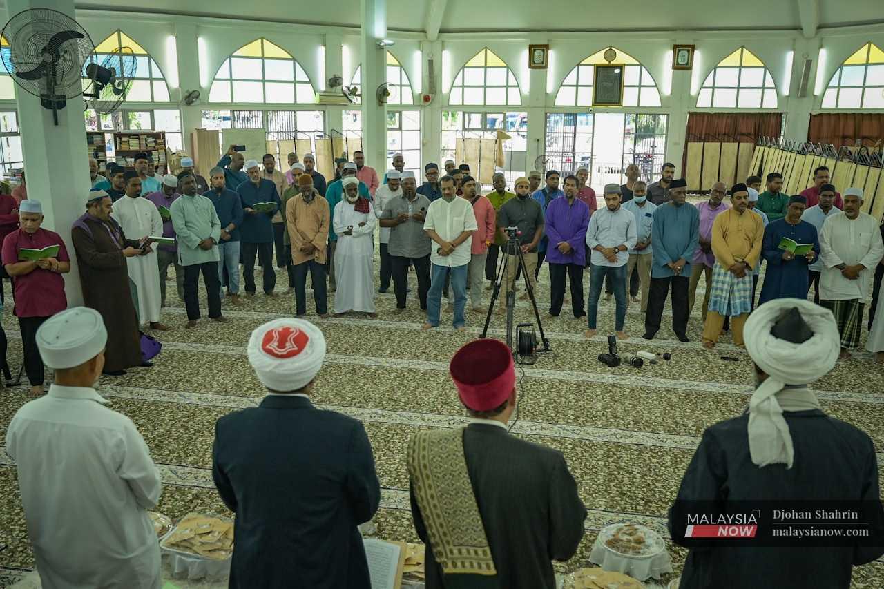 Participants stand up as they recite the salawat, poetic passages in Arabic in praise of Prophet Muhammad.
