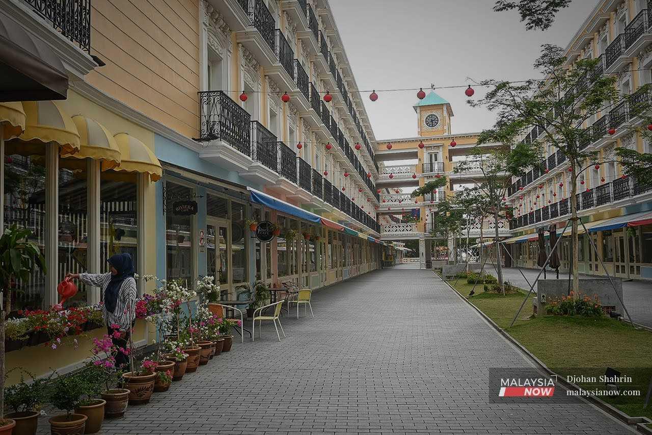 Seorang pekerja menyiram pokok di sekitar bangunan pusat bandar Melaka ketika pandemik Covid-19 tahun lalu.