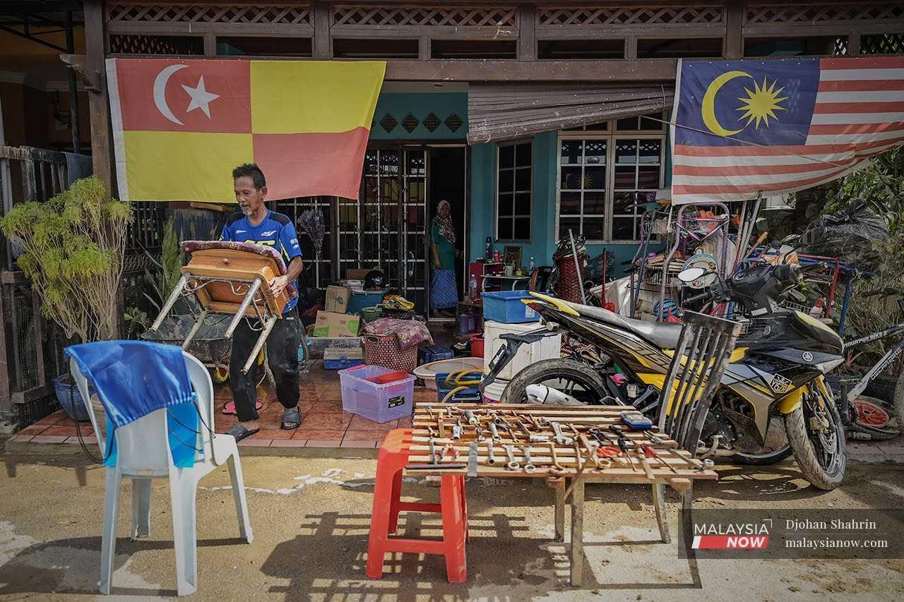 A man carries furniture to dry in the sun outside his house in Taman Sri Nanding, Selangor, after the massive floods that swept through Hulu Langat in December last year. 