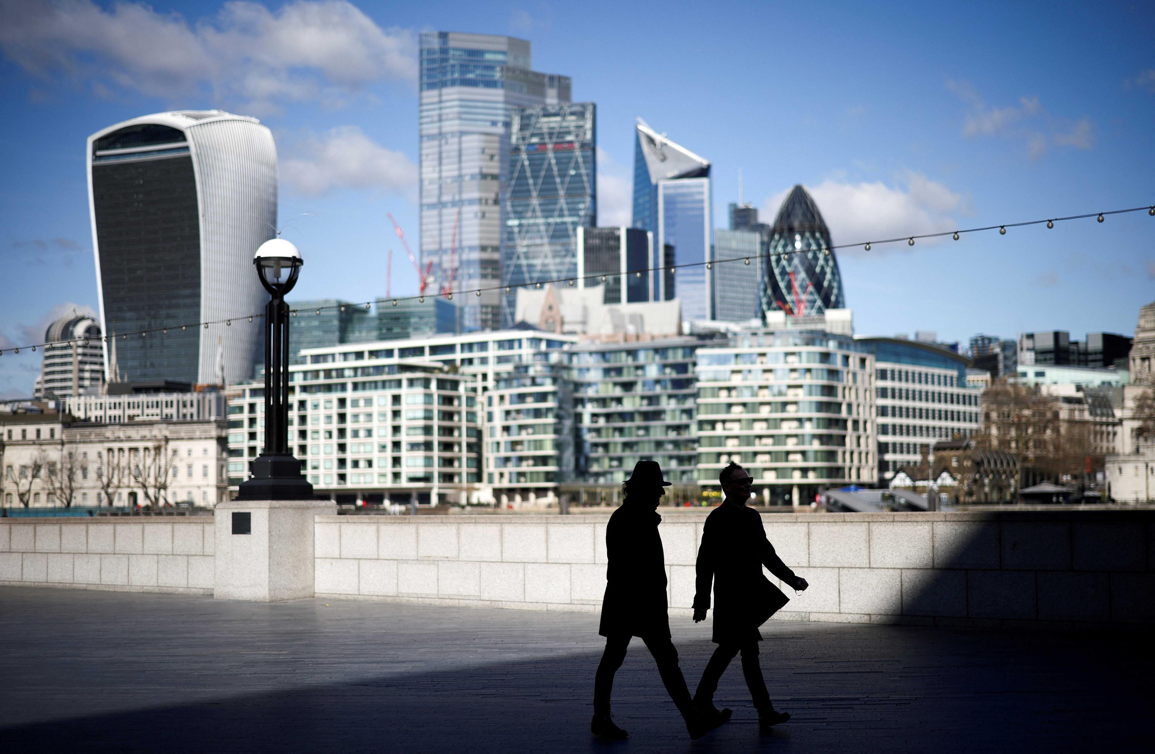 The City of London financial district can be seen as people walk along the south side of the River Thames in London, Britain, March 19, 2021. Photo: Reuters