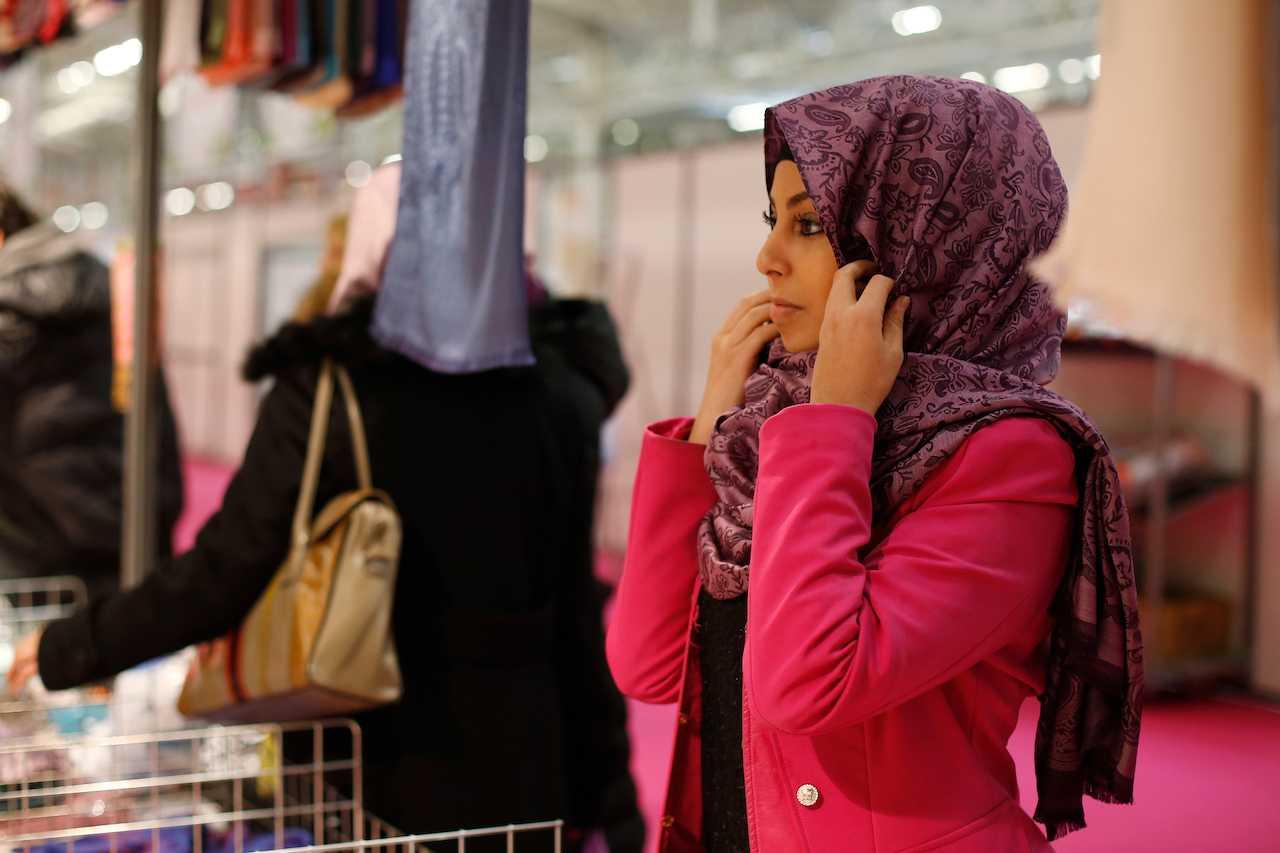 A picture taken on April 3, 2015 shows a visitor trying on a headscarf on a seller's stand during the 32nd Annual Meeting of France's Muslims, at Le Bourget Exhibition center, north of Paris. Photo: AFP