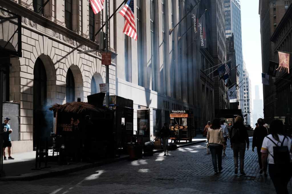 People walk along Wall Street by the New York Stock Exchange on Oct 07, in New York City. Photo: AFP