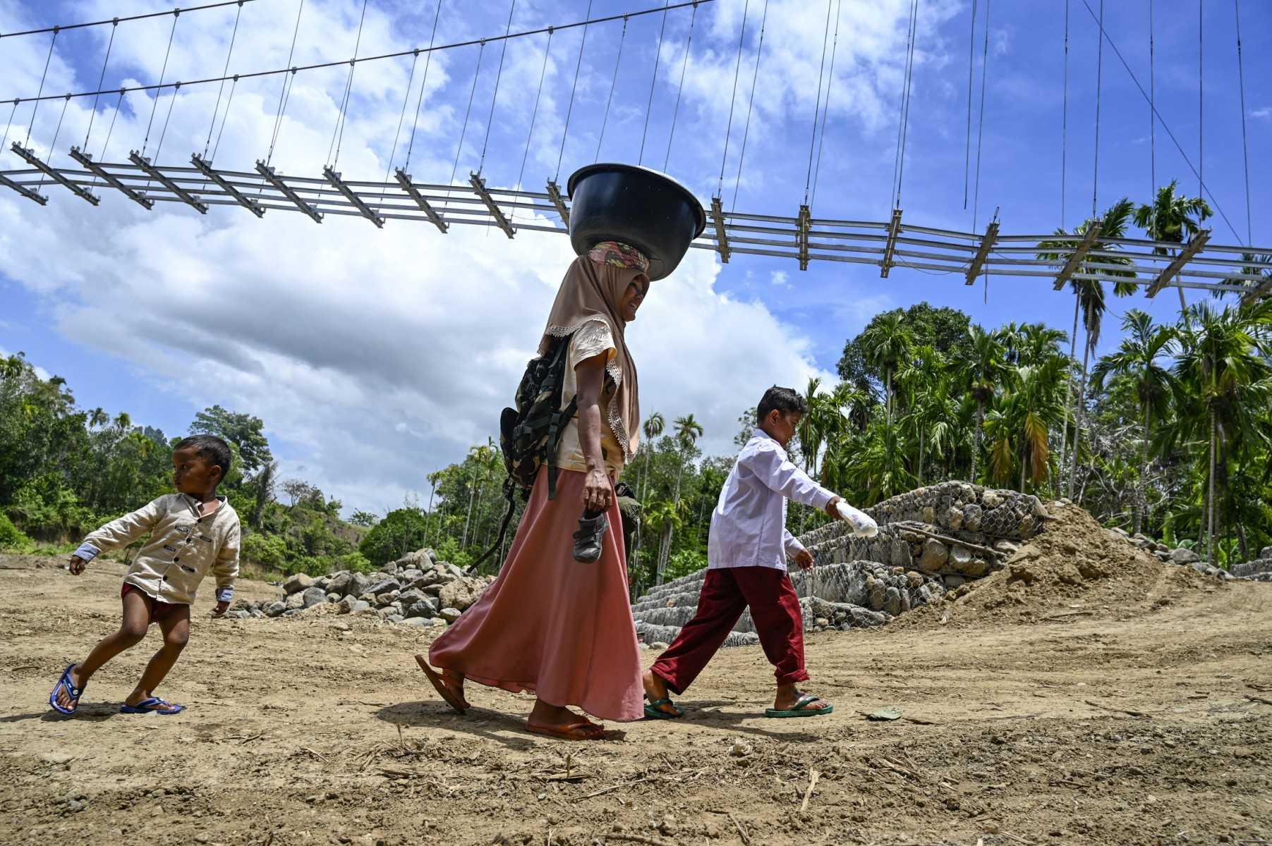 A woman and her children walk next to an unfinished suspension bridge at Siron village in Kuta Cot Glie, Aceh province on Oct 4. Photo: AFP