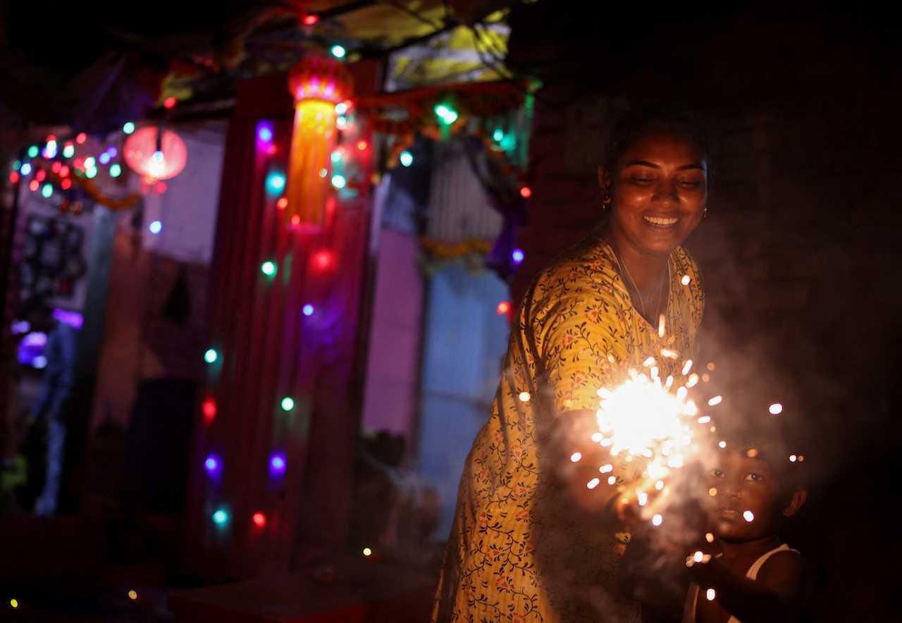 A woman and her son hold firecrackers during Deepavali, the Hindu festival of lights, in Mumbai, India, Nov 4, 2021. Photo: Reuters