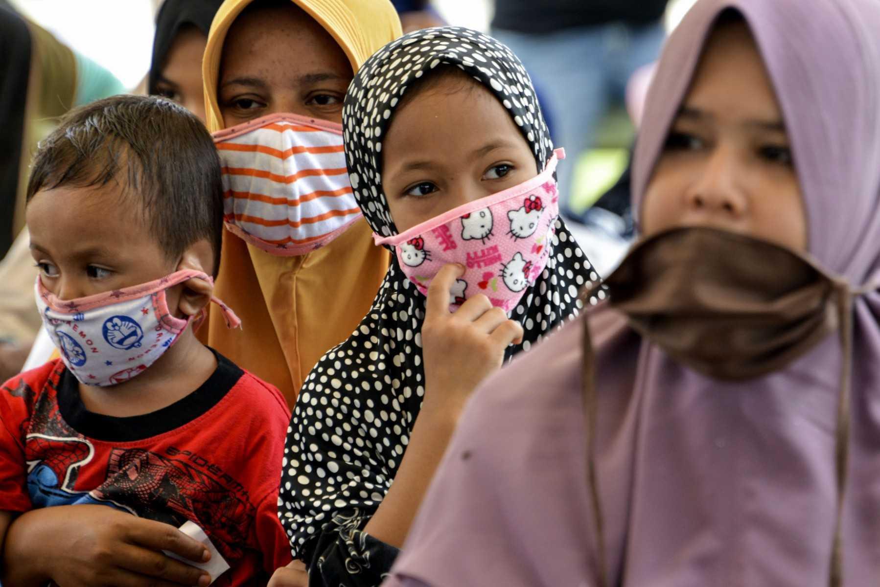 Dua orang kanak-kanak memakai pelitup muka ditemani ibu mereka. Lebih 200 kes kegagalan buah pinggang dalam kalangan kanak-kanak negara itu direkodkan tahun ini. Gambar: AFP