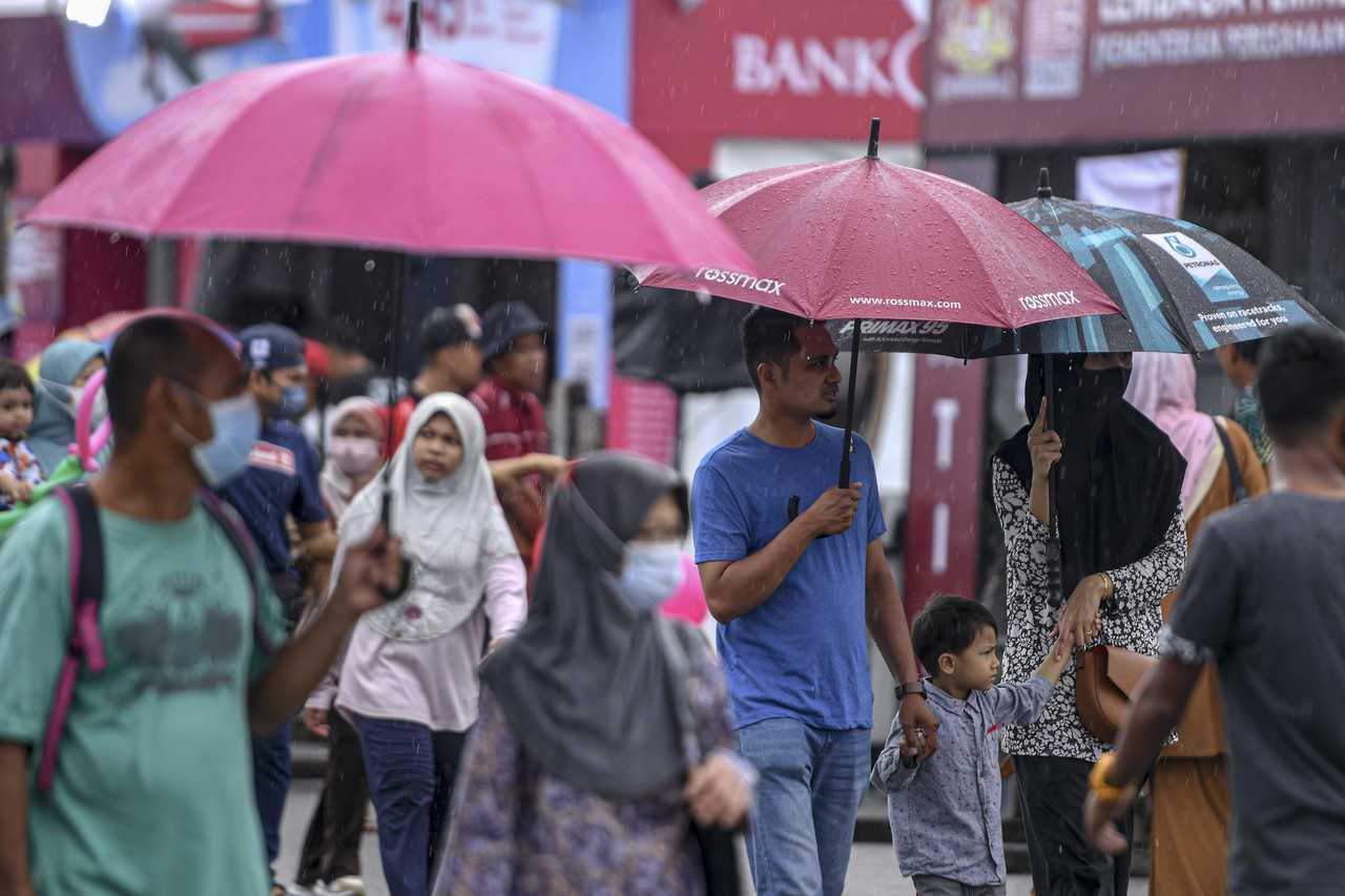 Pejalan kaki memakai payung ketika meredah hujan di Gong Badak, Kuala Nerus. Gambar: Bernama