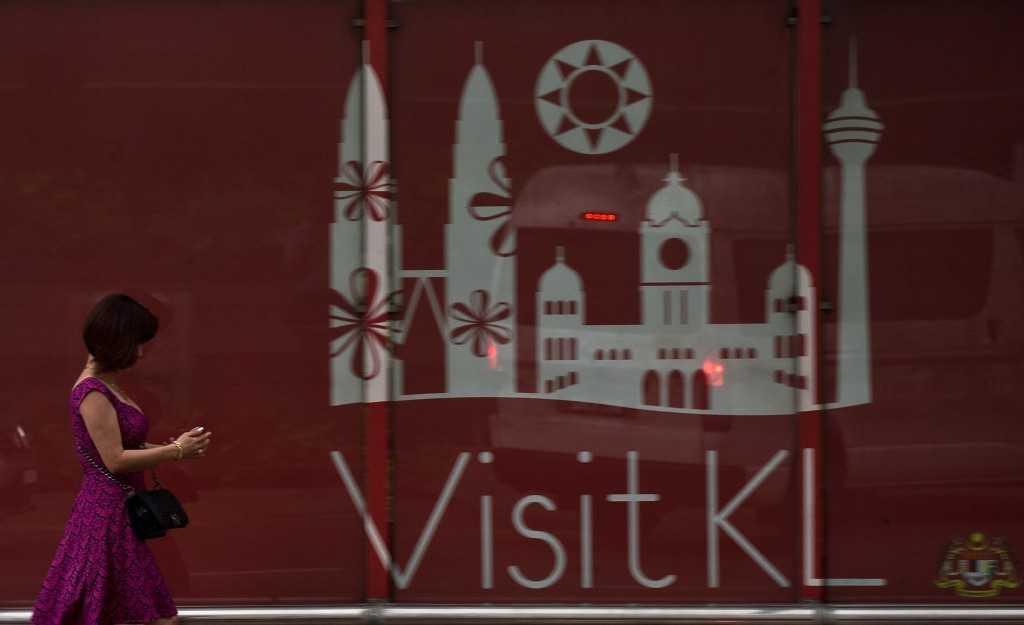 A woman walks past tourism advertising in the business hub of Kuala Lumpur on April 8, 2014. A terrorism expert says there are a number of factors that make Malaysia a natural target for governments in their efforts to silence dissent. Photo: AFP 
