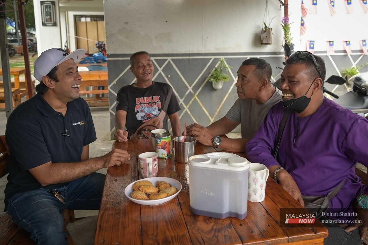 Baharudin Md Som (second from right) enjoys a conversation with some of the other residents at his stall at the Kerinchi low-cost flats in Kuala Lumpur. 
