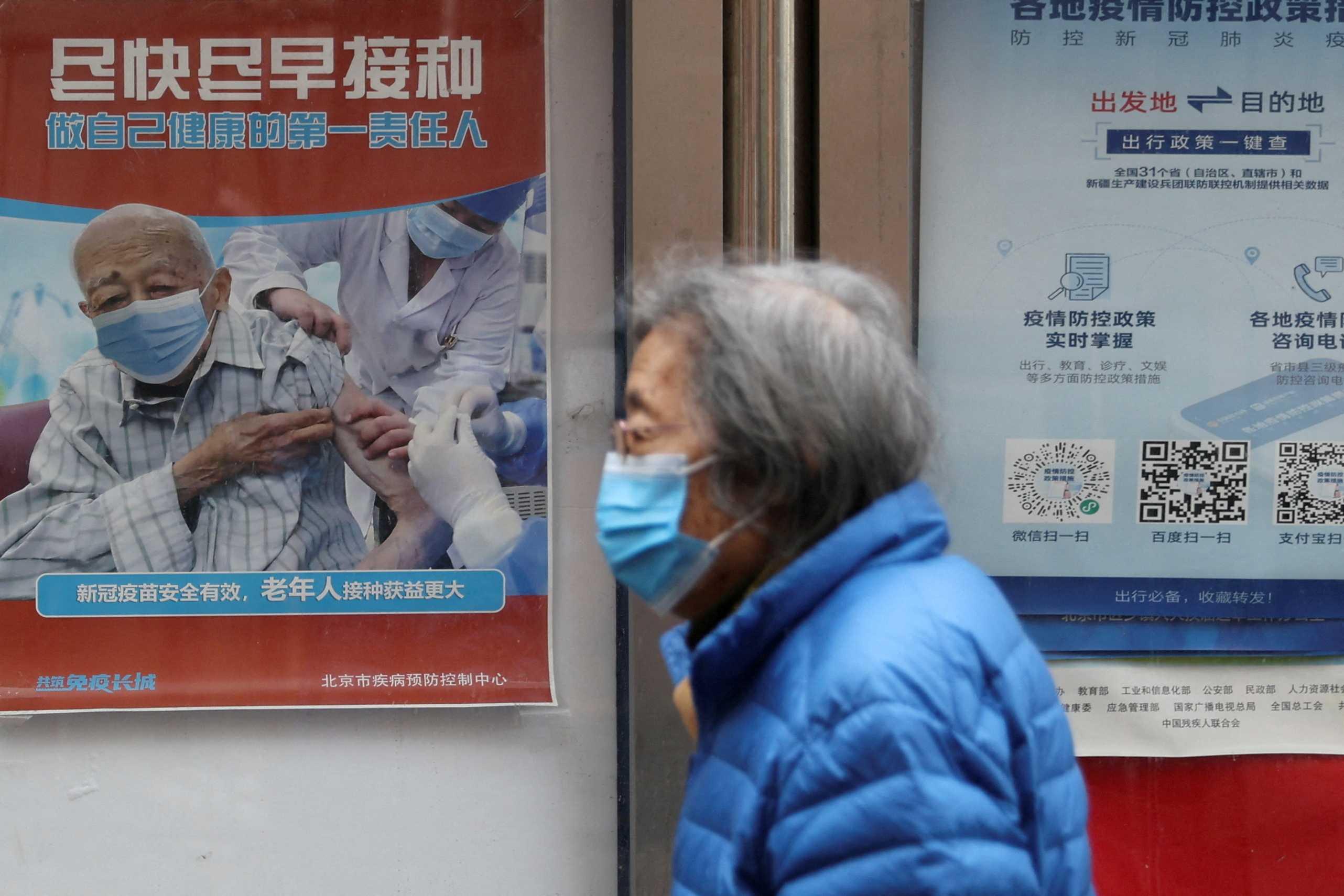 A person walks past a poster encouraging elderly people to get vaccinated against Covid-19, near a residential compound in Beijing, China March 30. Photo: Reuters