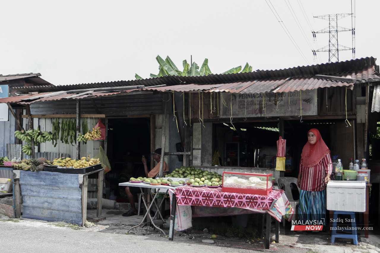 Sementara itu, Zubaidah Ismail menunggu pelanggan di gerai buah-buahannya di Kampung Manjoi Baru. Gerai itu adalah satu-satunya punca pendapatan sejak suaminya meninggal dunia akibat kanser lapan bulan lalu.

