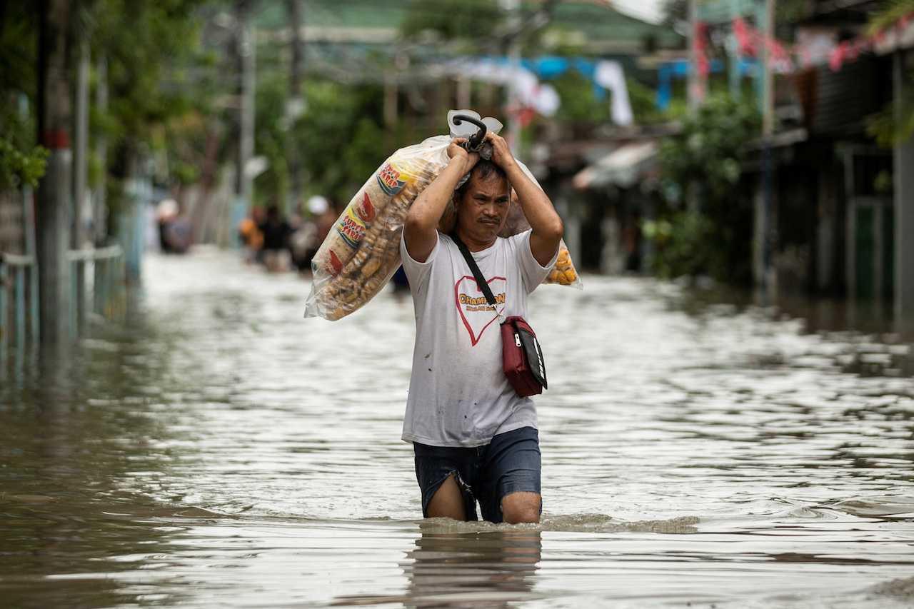 A vendor carries food products as he wades through a flooded street following heavy rains brought by tropical storm Nalgae, in Imus, Cavite province, Philippines, Oct 30. Photo: Reuters