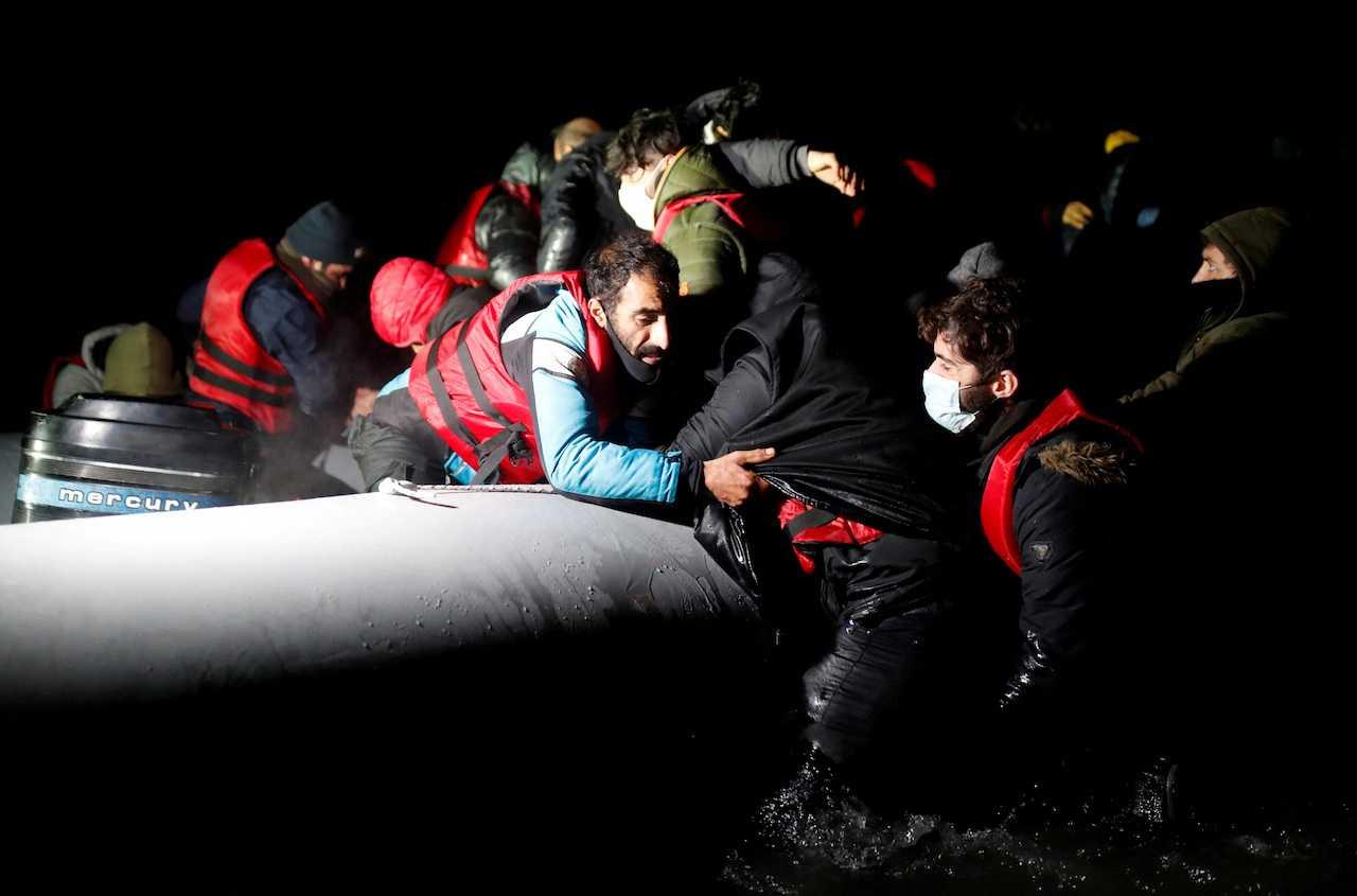 Migrants get on an inflatable dinghy as they leave the coast of northern France to cross the English Channel, in Wimereux near Calais, France, Dec 16, 2021. Photo: Reuters 