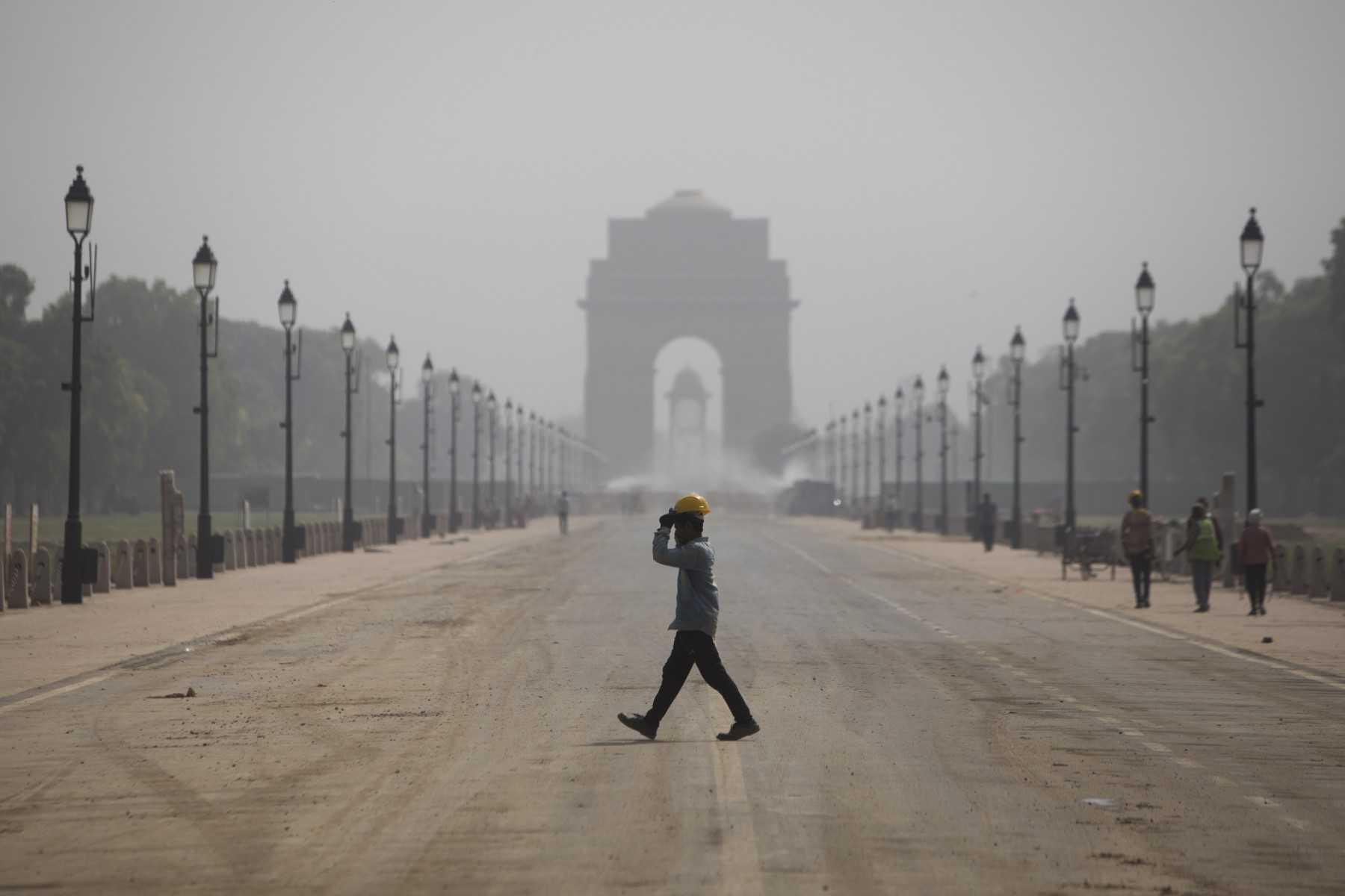 A construction worker walks across the under construction Rajpath, with Inda Gate seen in the background, in New Delhi on March 31. Photo: AFP