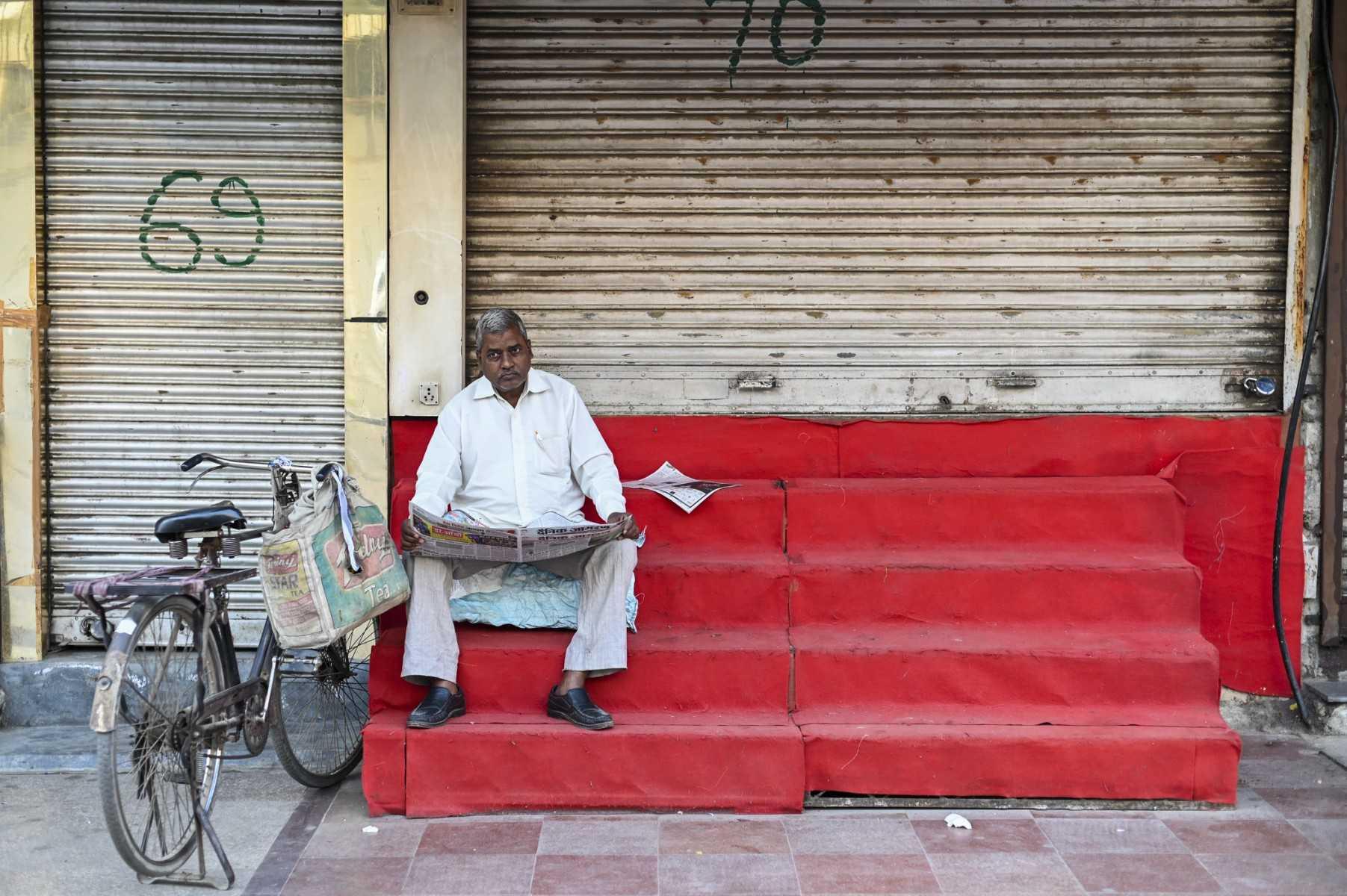 A man reads a newspaper in front of a closed shop in New Delhi on March 14. Photo: AFP