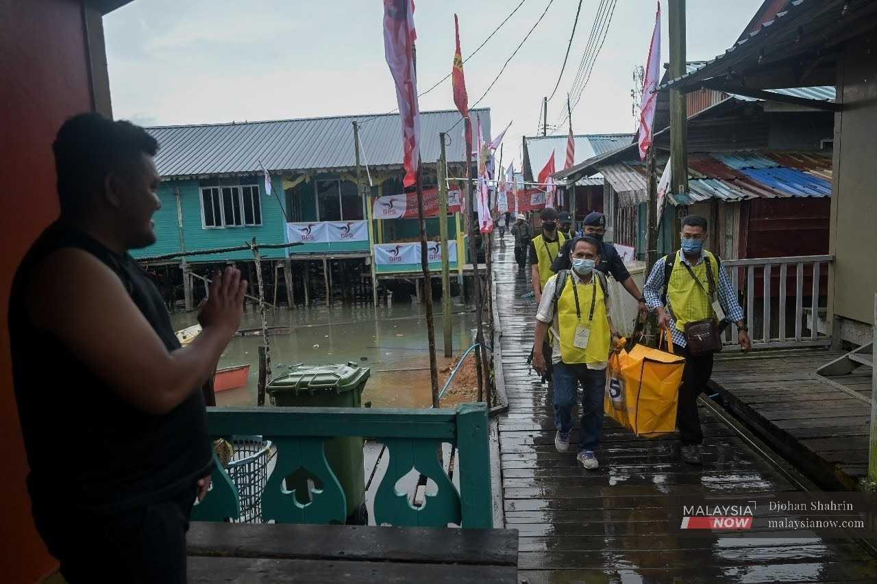 Petugas Suruhanjaya Pilihan Raya meredah hujan membawa peti undi sambil diiringi polis pada Pilihan Raya Negeri Sarawak Disember tahun lalu.