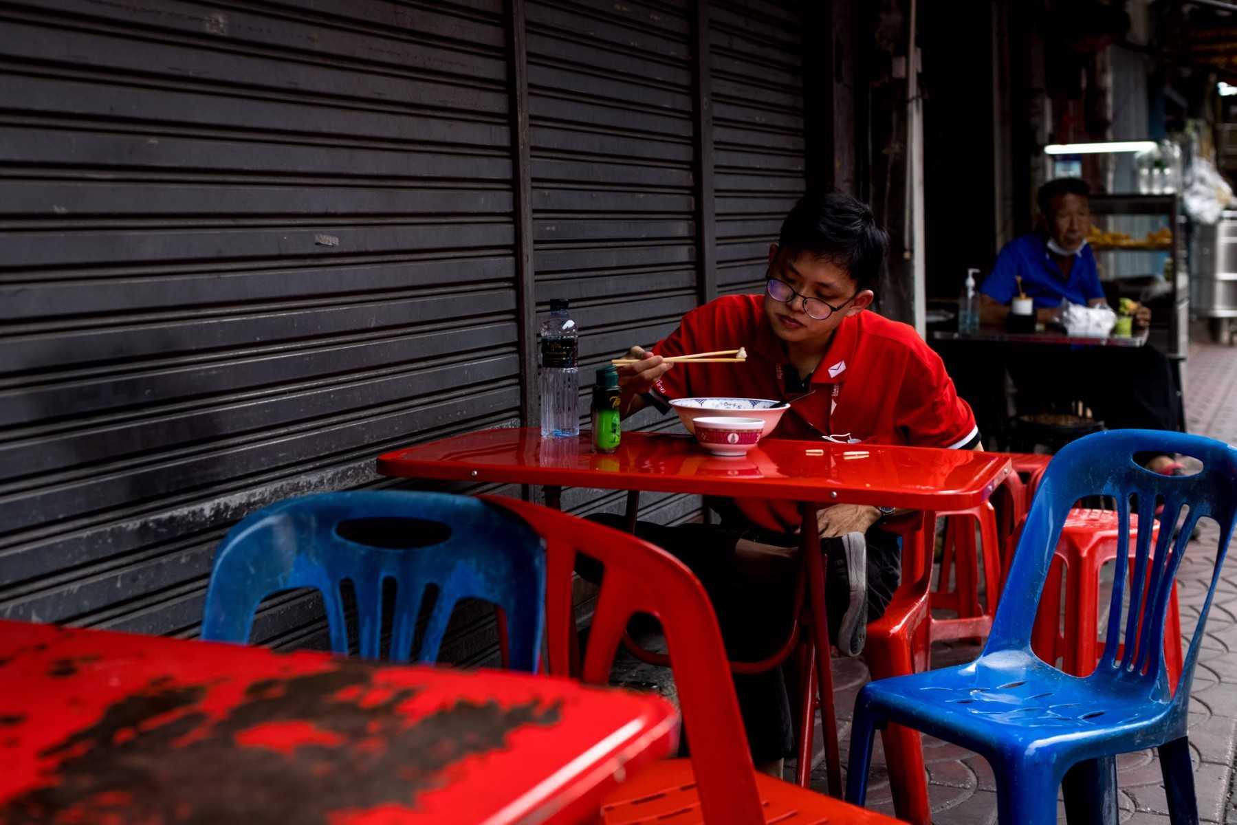A person eats a bowl of food at a street stall in Bangkok on Nov 9, 2021. The cybercrime rings first emerged in Cambodia, but have since moved into other countries in the region and are targeting more tech-savvy workers, including from India and Malaysia. Photo: AFP 