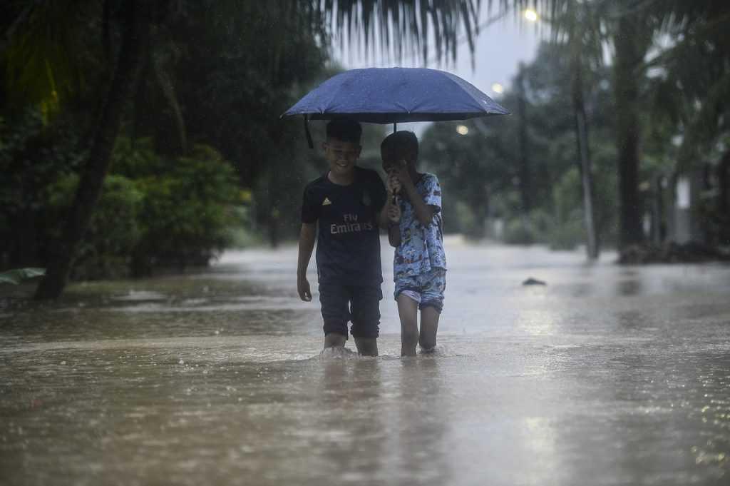 Dua kanak-kanak meredah banjir di kawasan kampung di Johor pada Disember tahun lalu. Gambar: Bernama