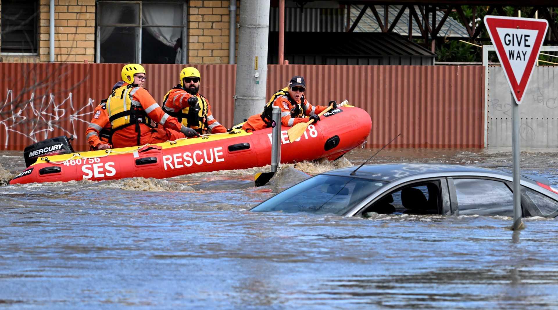 Emergency workers look at a submerged car on a flooded street in the Melbourne suburb of Maribyrnong on Oct 14. Photo: Reuters