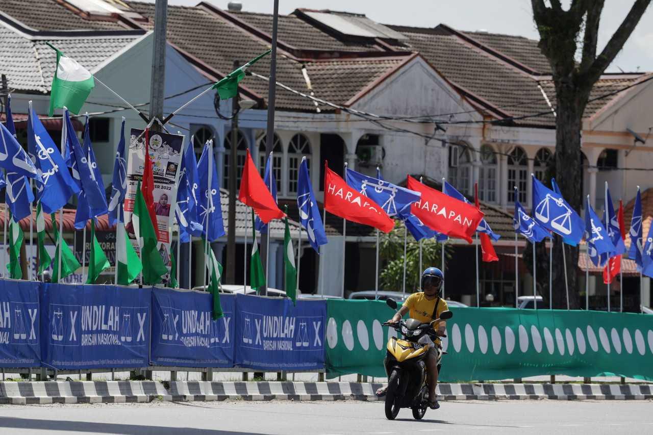 A motorcyclist passes the flags of various political parties at Jalan Sultan Omar in Kuala Terengganu, ahead of the 15th general election on Nov 19. Photo: Bernama