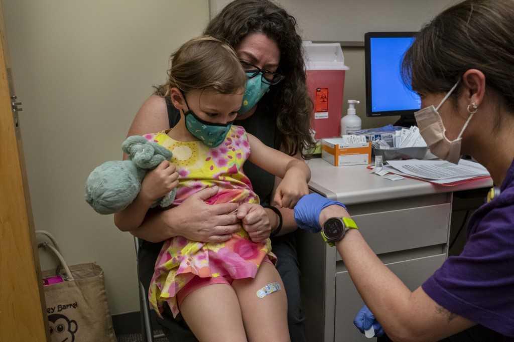 A young child sits on her mother's lap after receiving her first dose of the Pfizer Covid-19 vaccine in Seattle, Washington, on June 21. Photo: AFP
