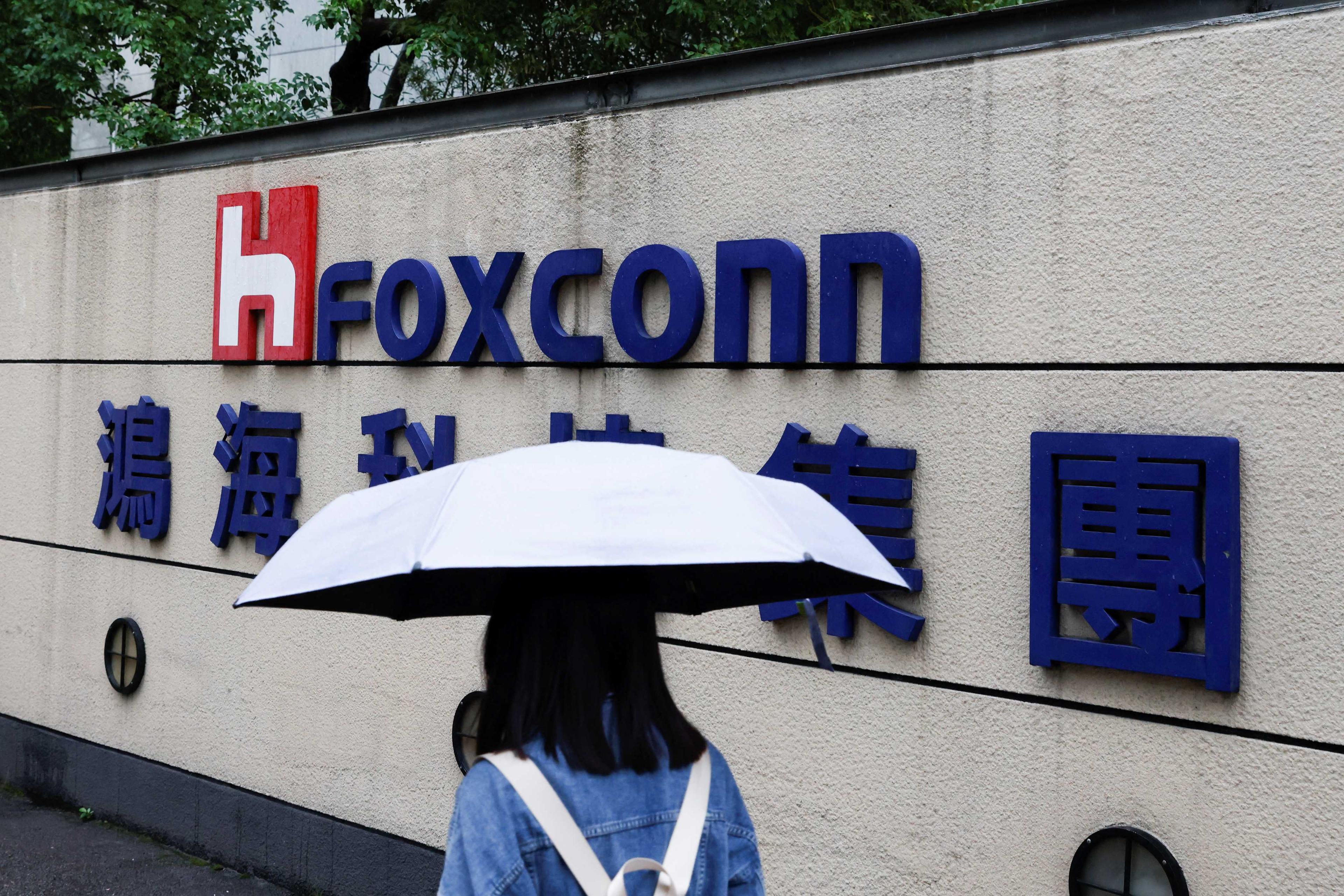 A woman carrying an umbrella walks past the logo of Foxconn outside a company's building in Taipei, Taiwan Oct 31. Photo: Reuters