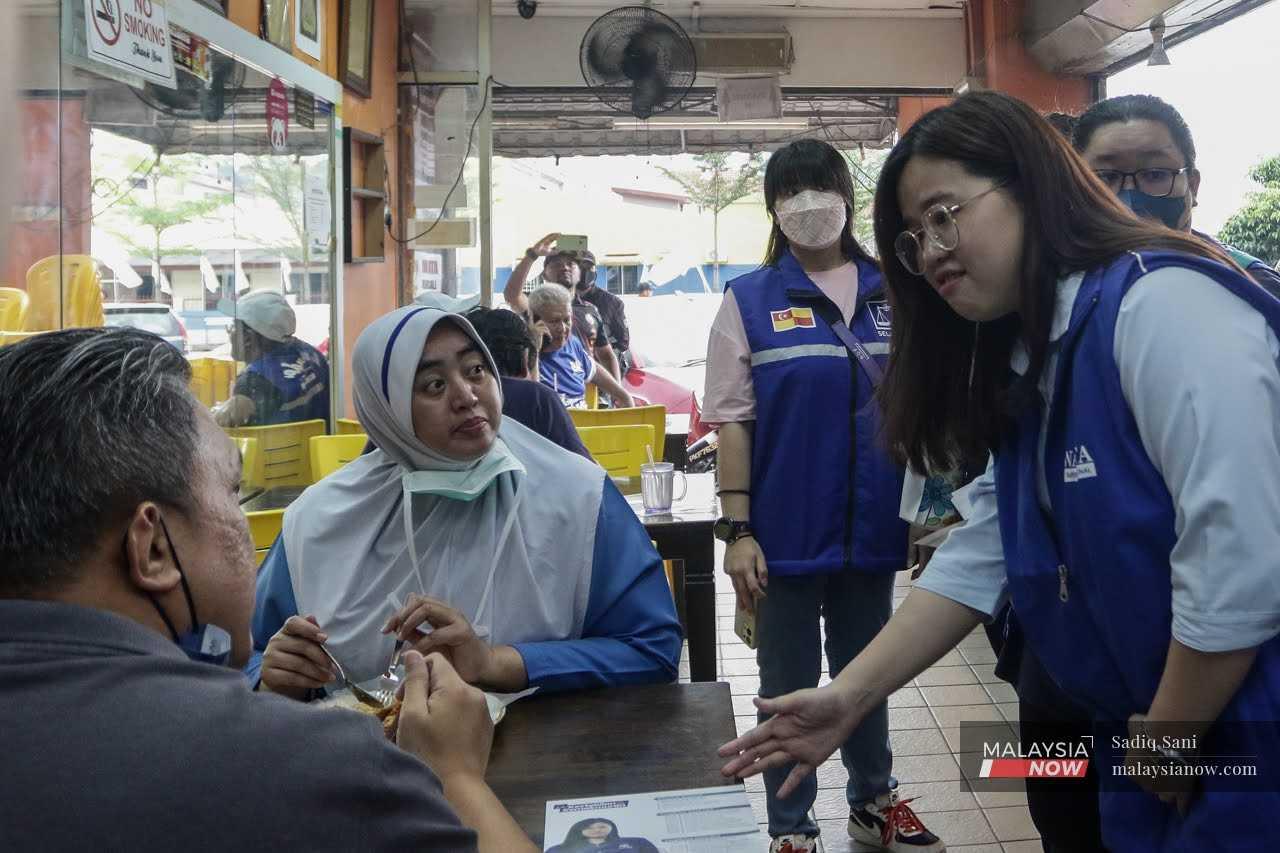 Barisan Nasional's Ivone Low Yi Wen makes her rounds as well, greeting customers at a restaurant in Taman Kosas.