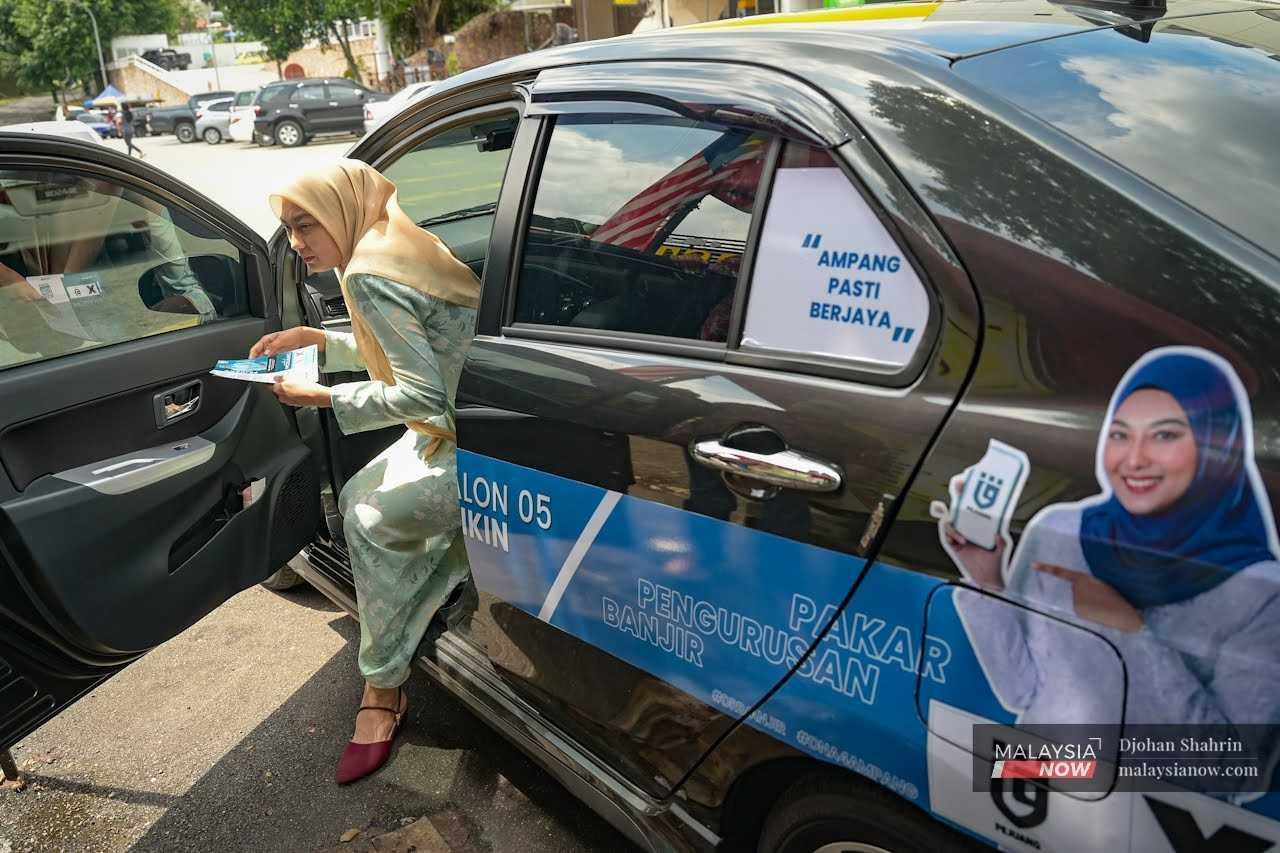 Pejuang's Nurul Ashikin Mabahwi arrives in a Perodua Bezza outfitted for the general election to meet with constituents ahead of the Nov 19 polls. 