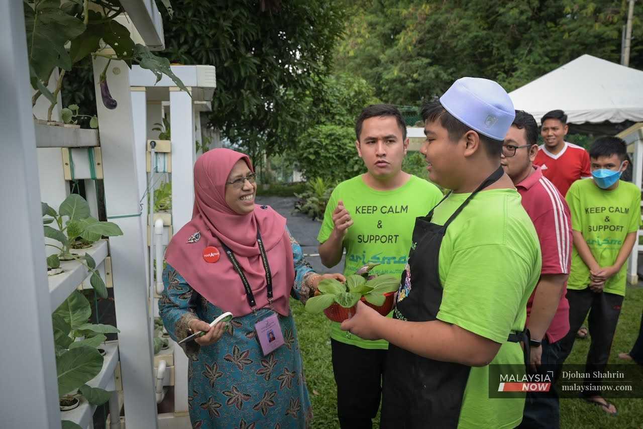 At Arisma, an academy for autistic youth, she speaks with a teenager after taking a tour of the centre's hydroponic vegetable farm. 