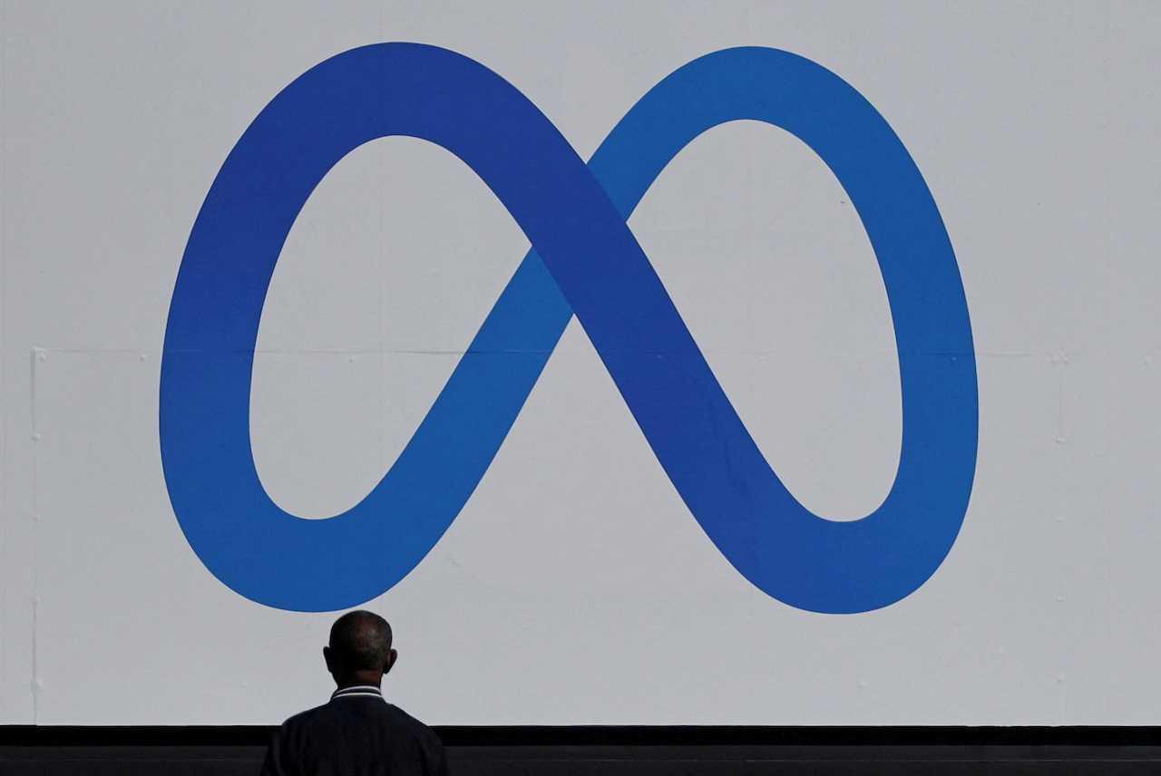 A man stands in front of a sign of Meta, the new name for the company formerly known as Facebook, at its headquarters in Menlo Park, California, Oct 28, 2021. Photo: Reuters