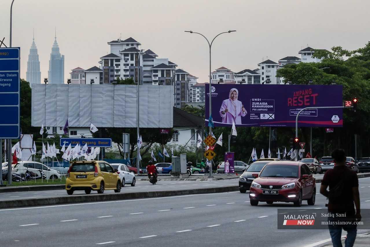 Traffic passes beneath a billboard in Ampang featuring incumbent Zuraida Kamaruddin and her campaign for the general election. 
