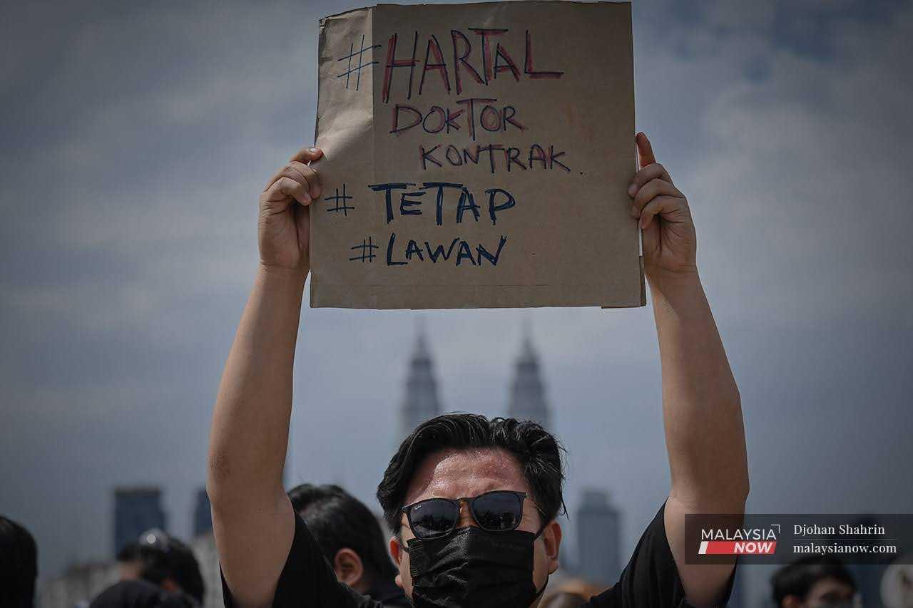 A contract doctor holds up a placard during a peaceful strike to protest the treatment of contract medical officers at Hospital Kuala Lumpur in July last year.