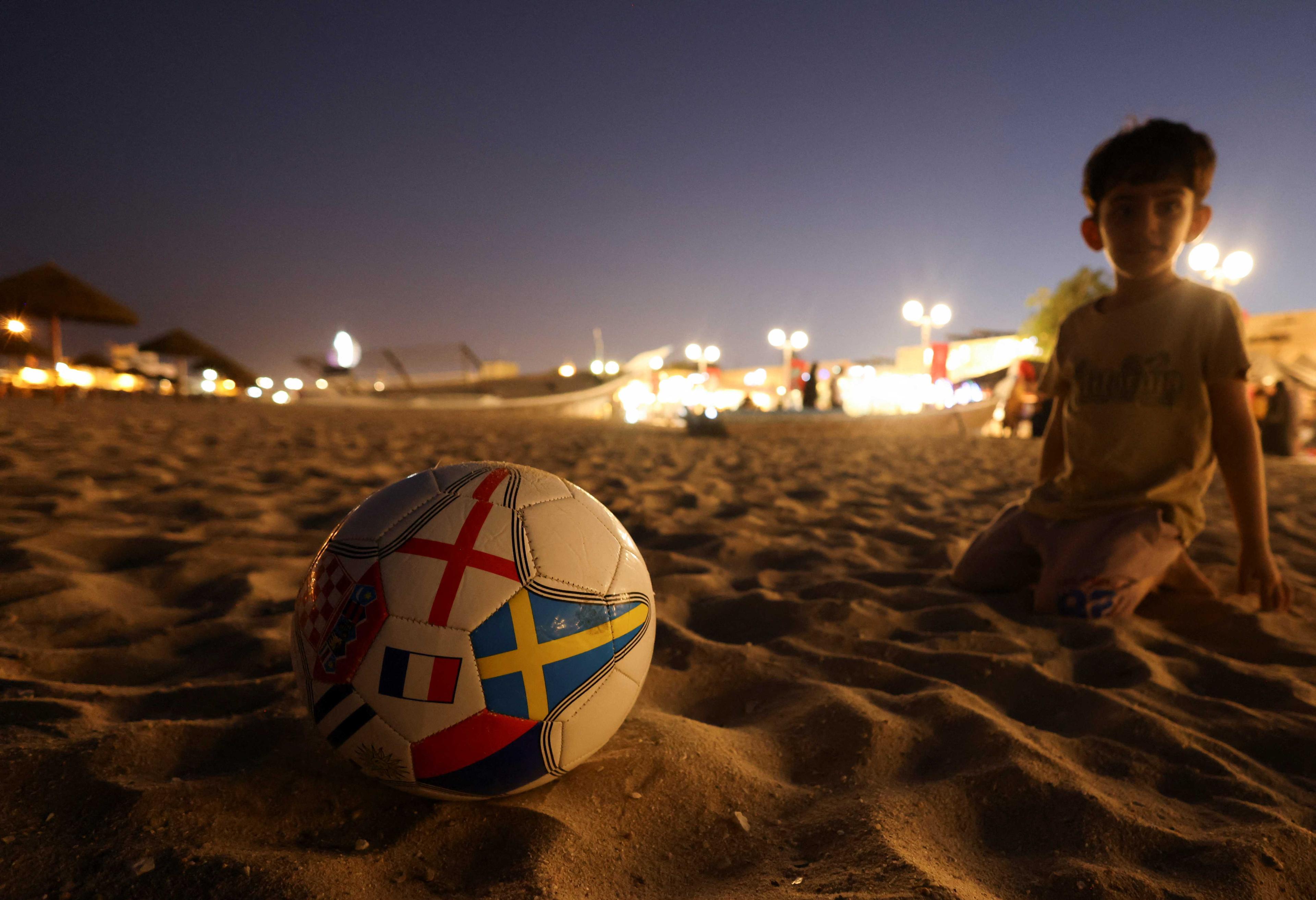 A boy plays with a football decorated with flags, ahead of 2022 Fifa World Cup soccer tournament, in Al Wakrah, south of Doha, Qatar, Nov 10. Photo: Reuters