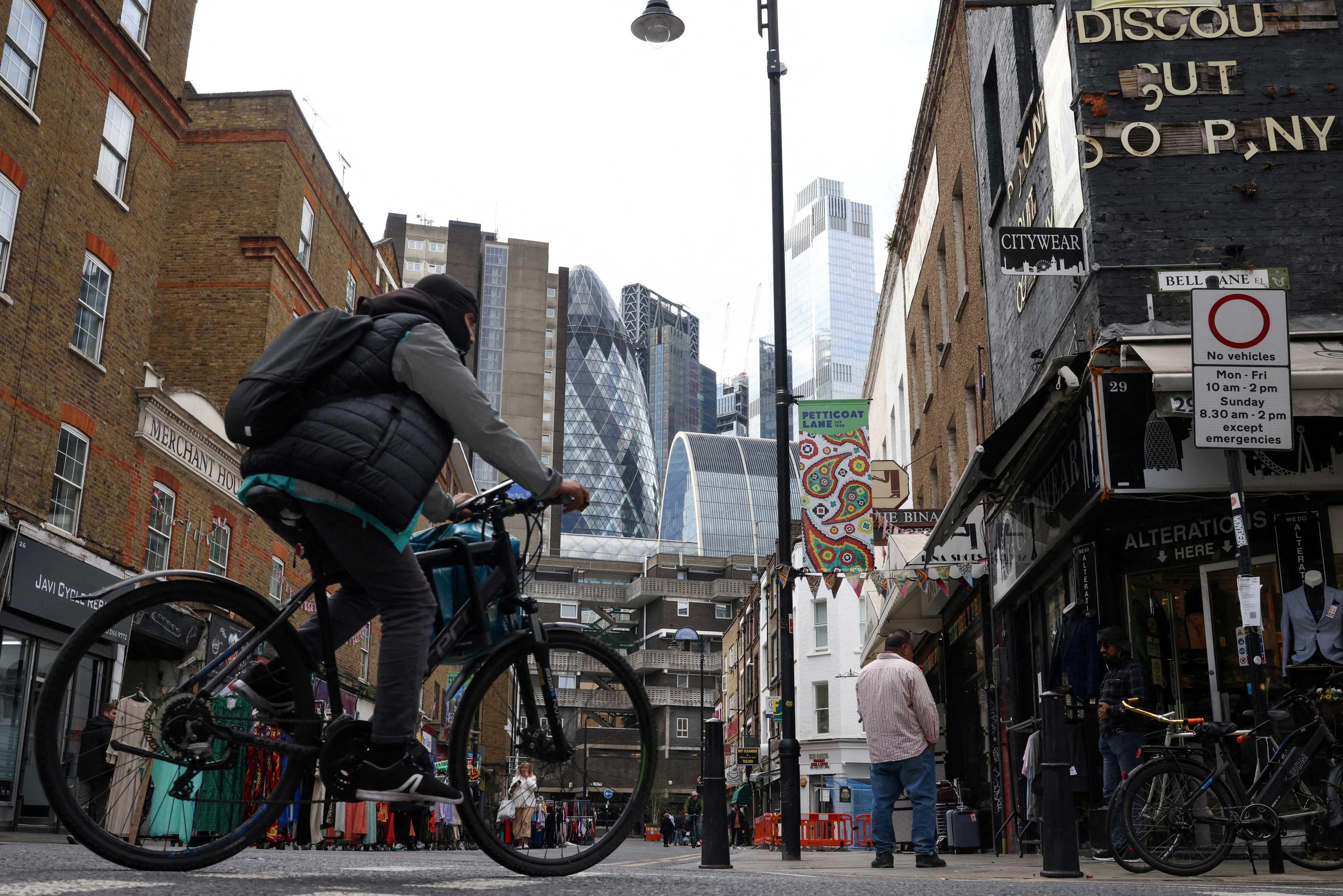 A person cycles through the Petticoat Lane Market, with the City of London financial district seen in the distance, in London, Britain, Oct 3. Photo: Reuters