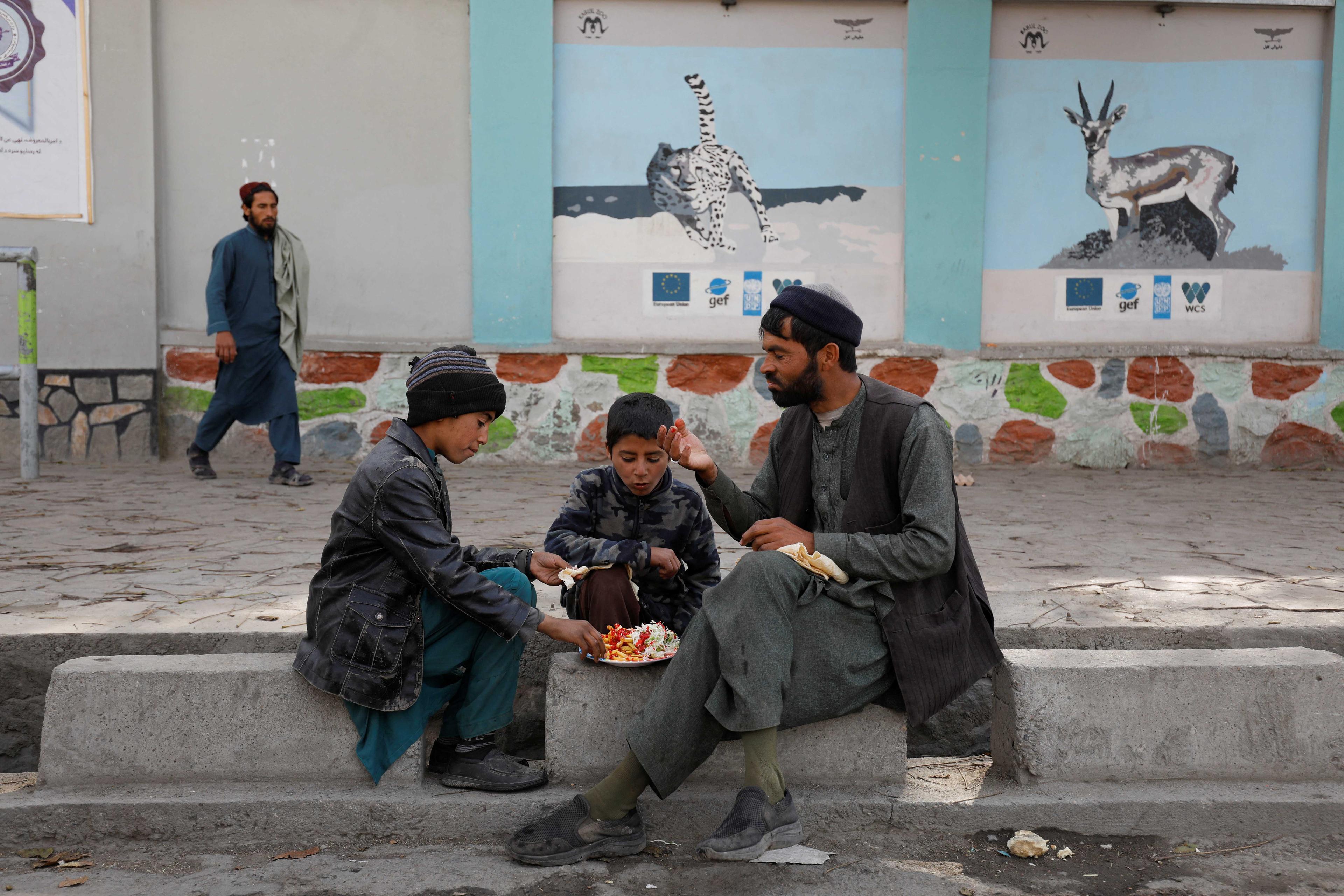 Afghan man and his children eat food in a street in Kabul, Afghanistan, Nov 9. Photo: Reuters 