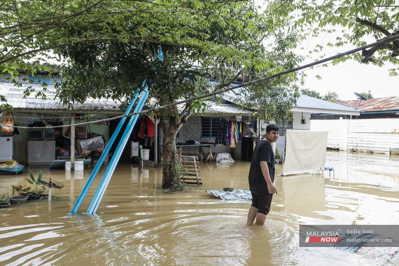 Seorang lelaki meredah air banjir di paras betis untuk pulang ke rumahnya.