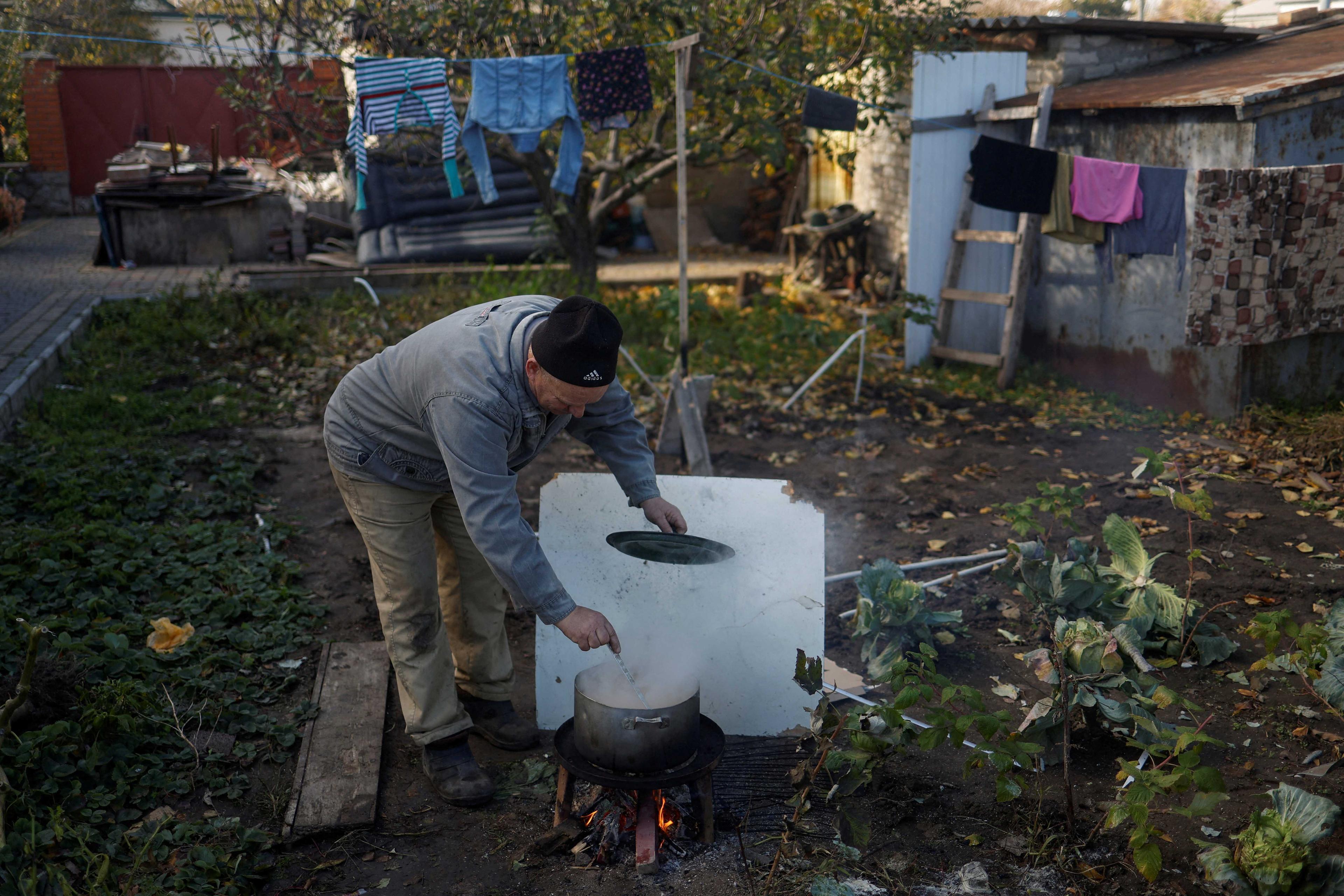 A man cooks food over wood in a backyard of a house of his relatives, which was destroyed during a recent Russian military attack in the town of Nikopol, Dnipropetrovsk region, Ukraine Nov 7. Photo: Reuters