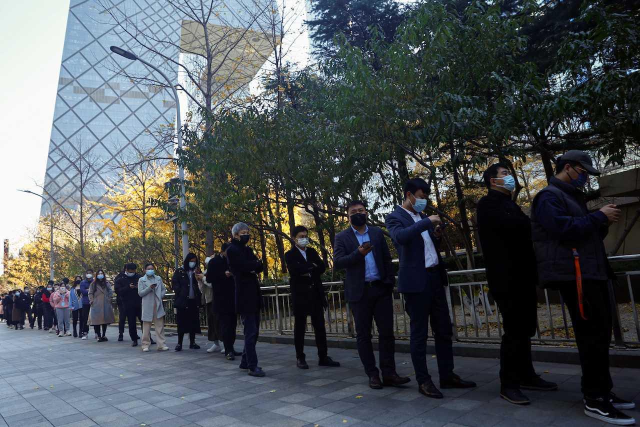 People line up to take a nucleic acid test for Covid-19 at a testing booth near an office building in the central business district in Chaoyang, Beijing, China, Nov 15. Photo: Reuters