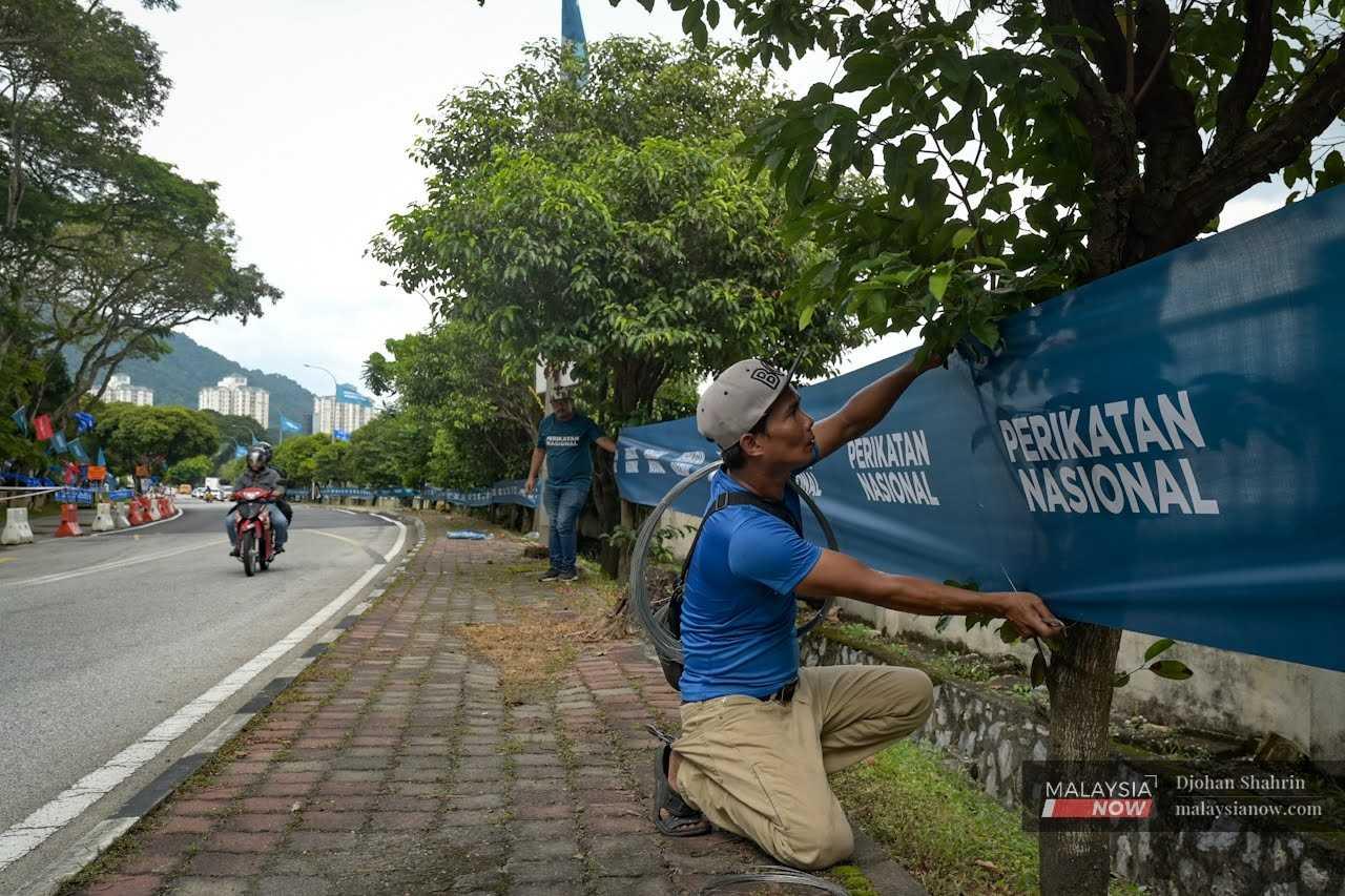Party workers put up Perikatan Nasional banners in Keramat, Kuala Lumpur, ahead of the general election.