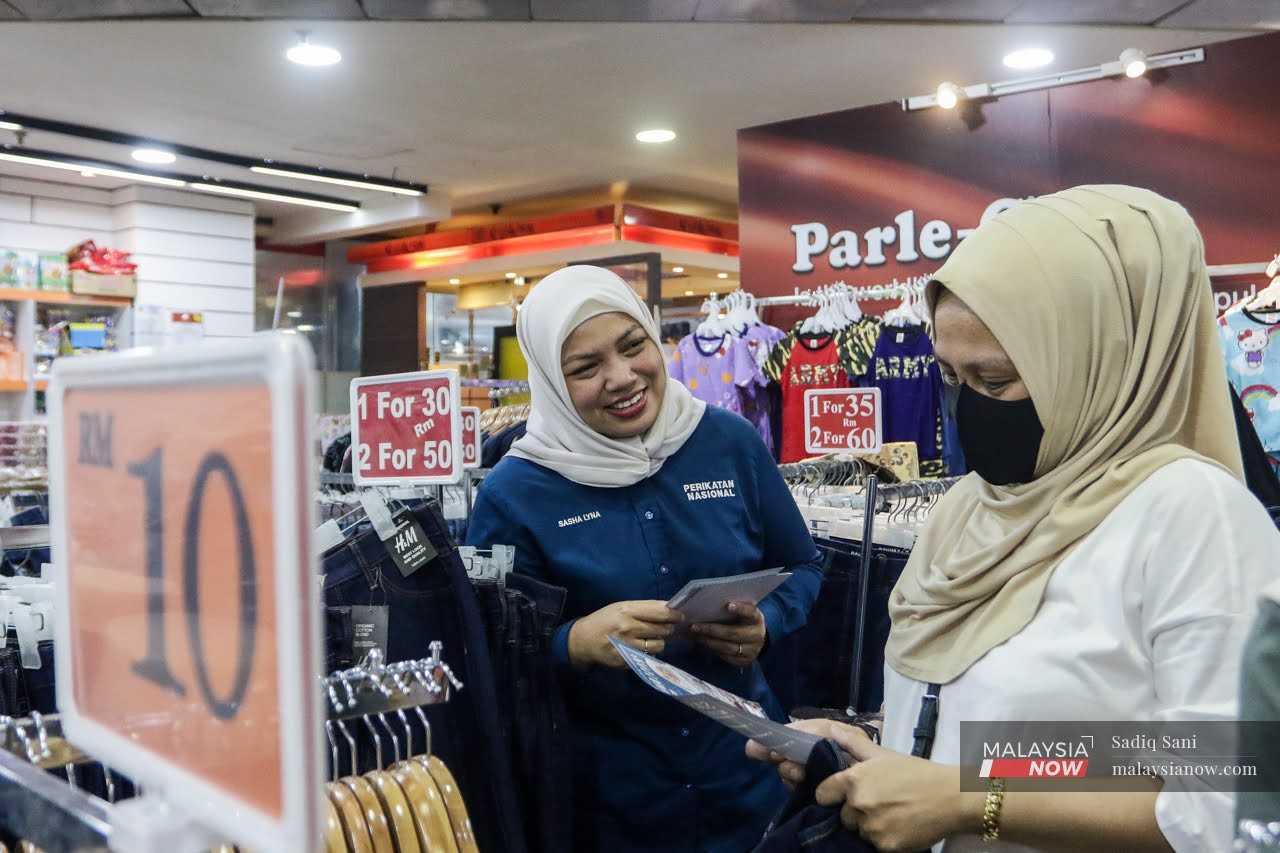 Perikatan Nasional candidate Sasha Lyna Abdul Latiff speaks to a woman during a walkabout in Ampang Point ahead of the general election. 
