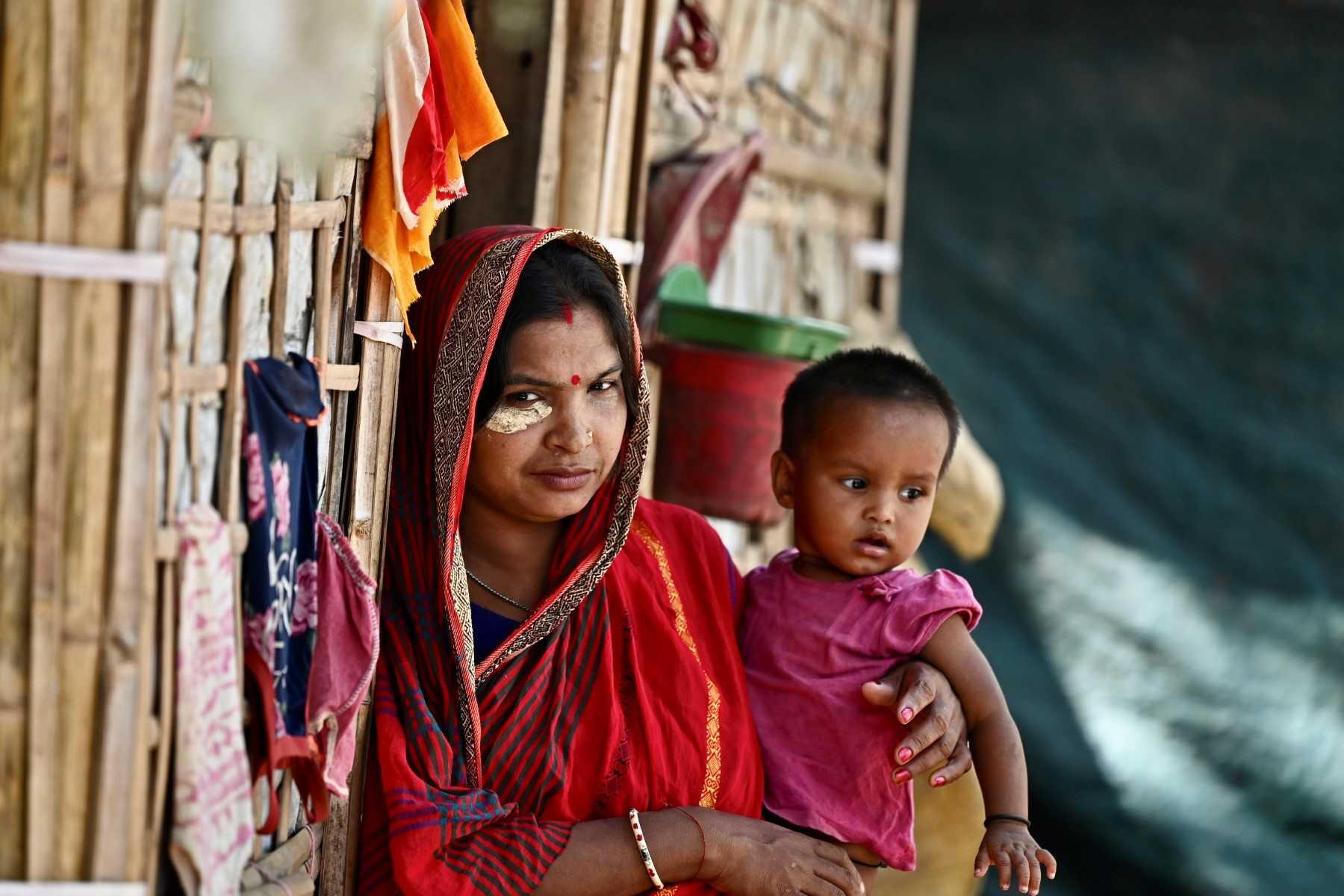 A Rohingya refugee woman carries a child while standing outside her makeshift hut at a Hindu Rohingya camp in Ukhia on Aug 24. Photo: AFP
